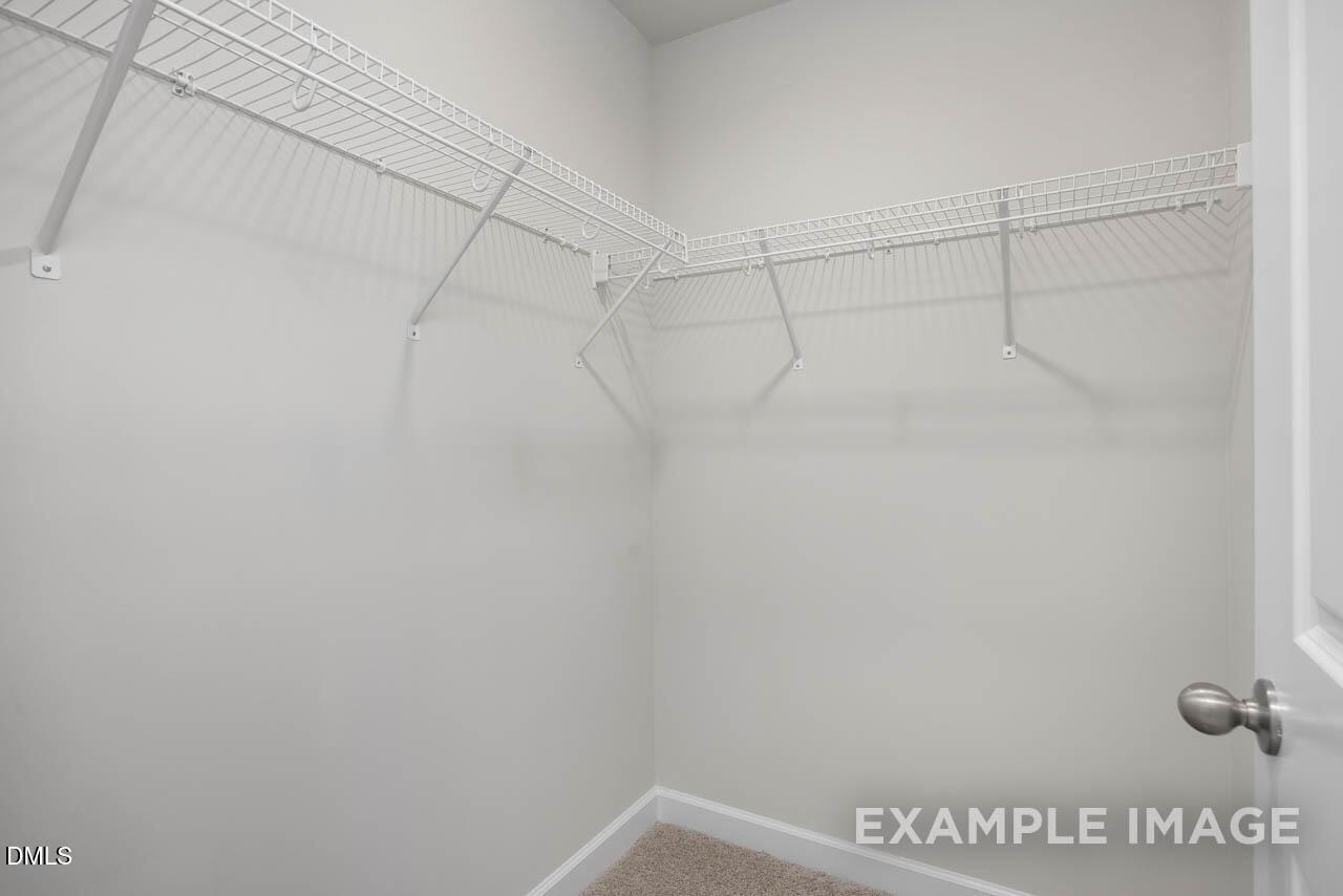 Spacious walk-in closet with white wire shelving and hanging rods in Davidson Homes Adalynn A, Lillington, NC