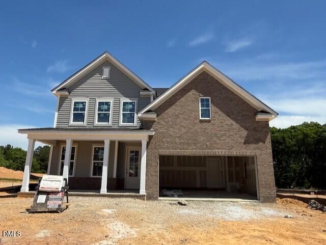 Two-story Davidson Homes Hickory II C with brick siding, covered front porch, open two-car garage in Woodland Crossing, Zebulon, NC