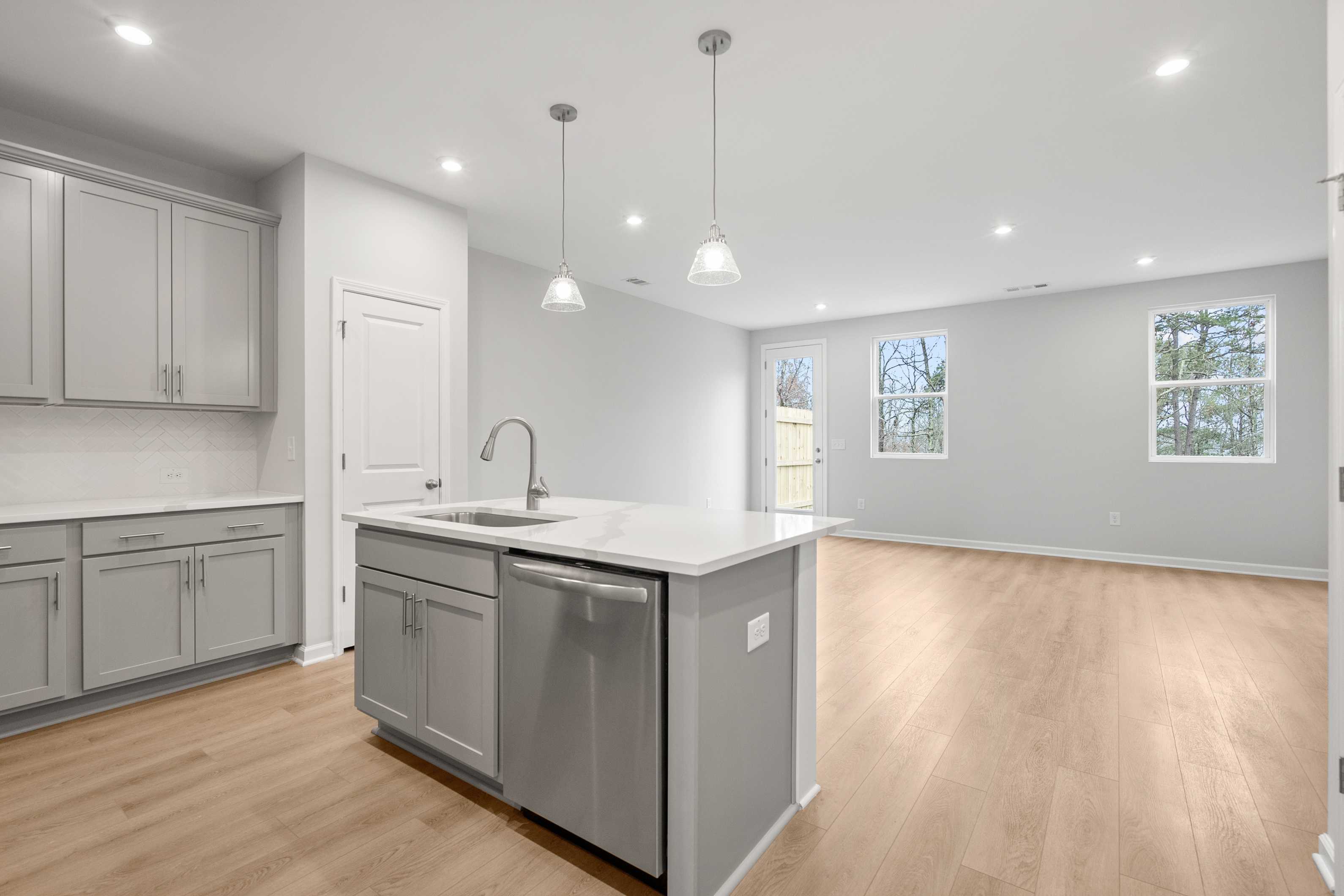 Spacious kitchen in The Durant A by Davidson Homes featuring gray shaker cabinets, quartz island, stainless sink, and open layout