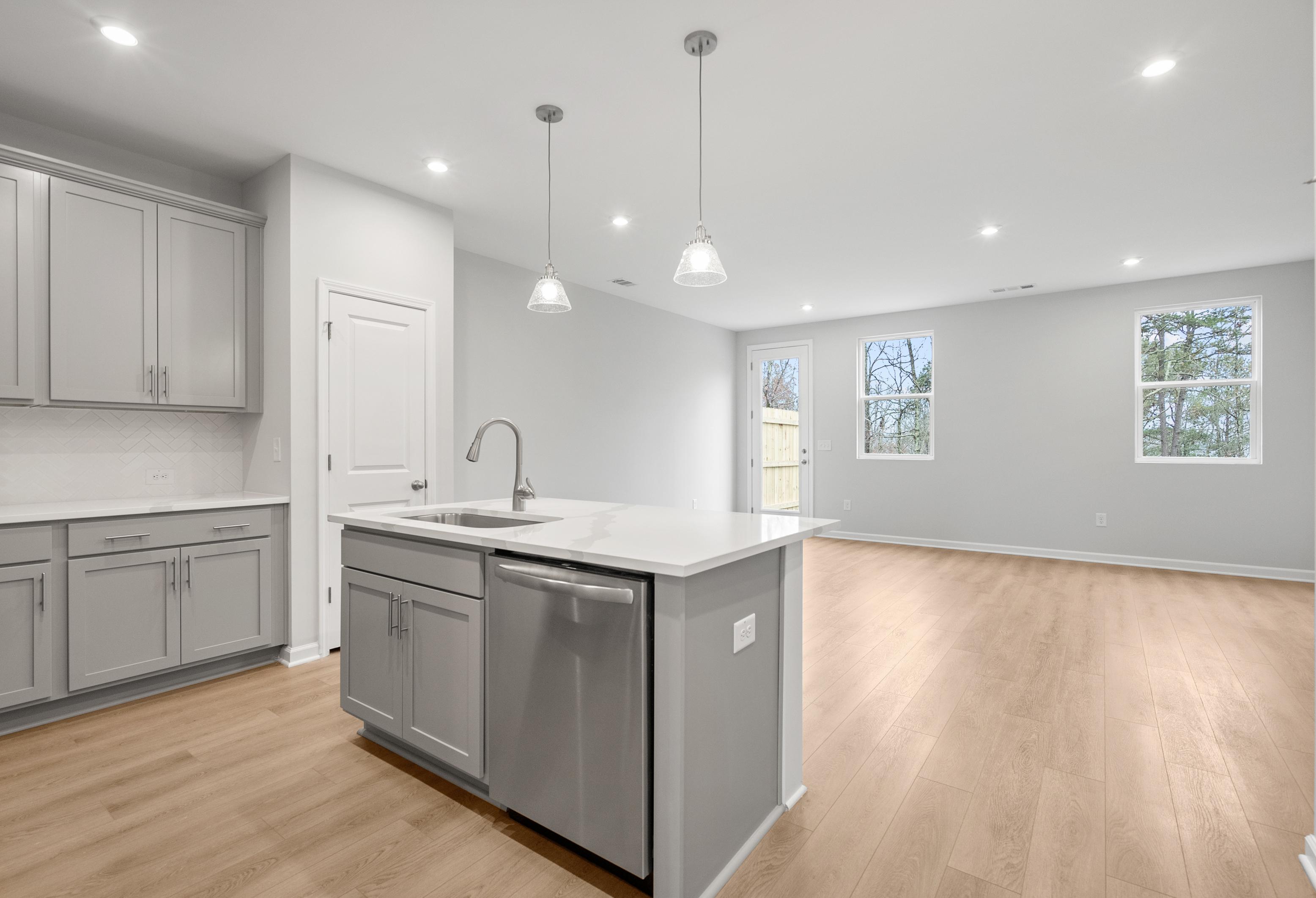 Spacious kitchen in The Durant A by Davidson Homes featuring gray shaker cabinets, quartz island, stainless sink, and open layout