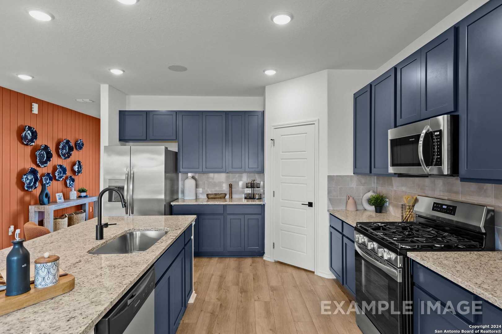 Modern navy kitchen with granite island, stainless appliances, blue cabinets in Davidson Homes The Douglas G, Bricewood San Antonio