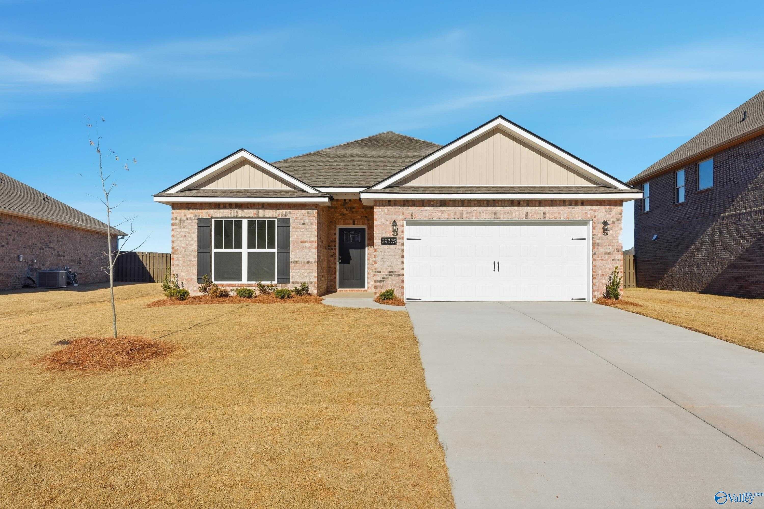 Beige brick ranch-style home with 2-car garage, driveway, and front landscaping in Creekside, Harvest, Alabama - Davidson Homes Everett plan