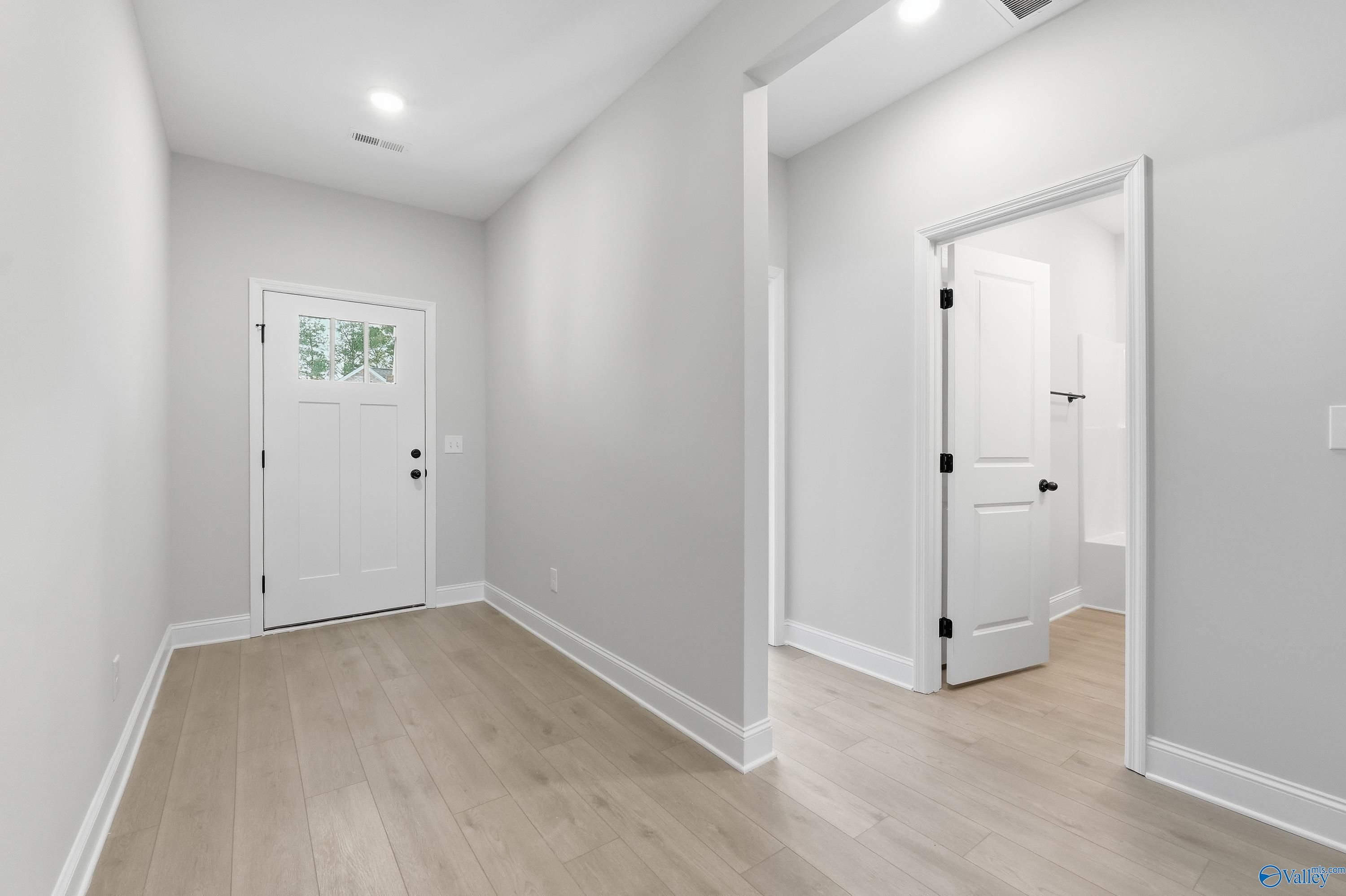 Bright entry hallway with hardwood floors, gray walls, and white doors in Davidson Homes The Daphne C, Ricketts Farm, Athens AL