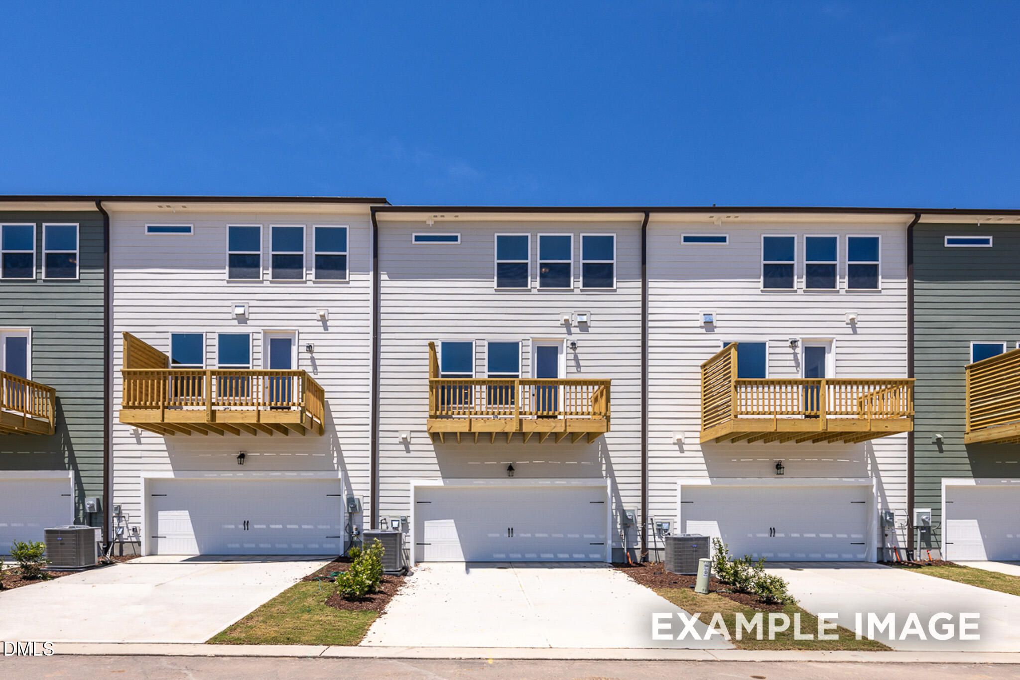 3-story townhomes with white siding, wooden balconies, and 2-car garages at Camden Park in Knightdale, North Carolina.
