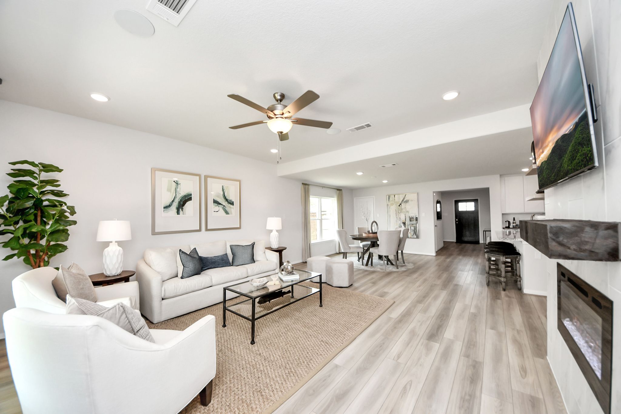 Open-concept living room at Sunterra in Katy, TX by Davidson Homes featuring light wood floors and a modern fireplace.