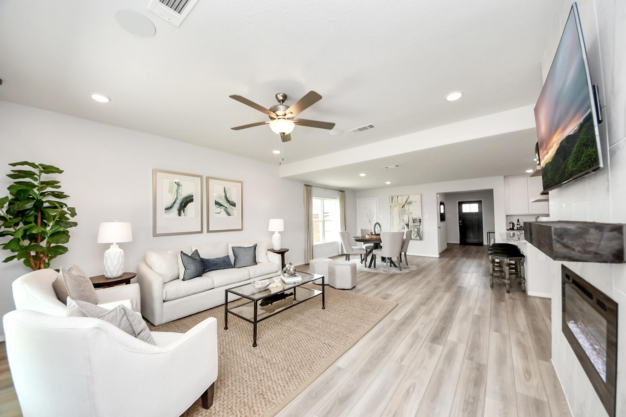 Open-concept living room at Sunterra in Katy, TX by Davidson Homes featuring light wood floors and a modern fireplace.
