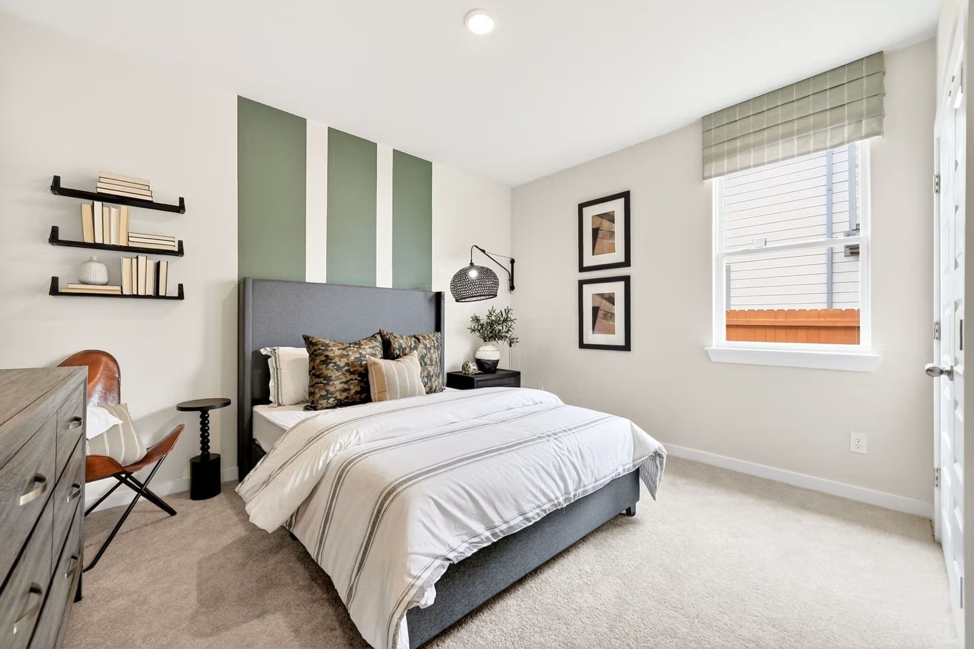 Modern guest bedroom with sage green accent wall in The Laurel I floor plan at Davidson Homes in Heartland, Texas.