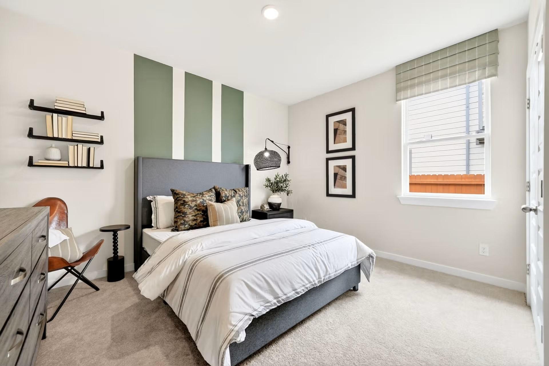 Modern guest bedroom with sage green accent wall in The Laurel I floor plan at Davidson Homes in Heartland, Texas.