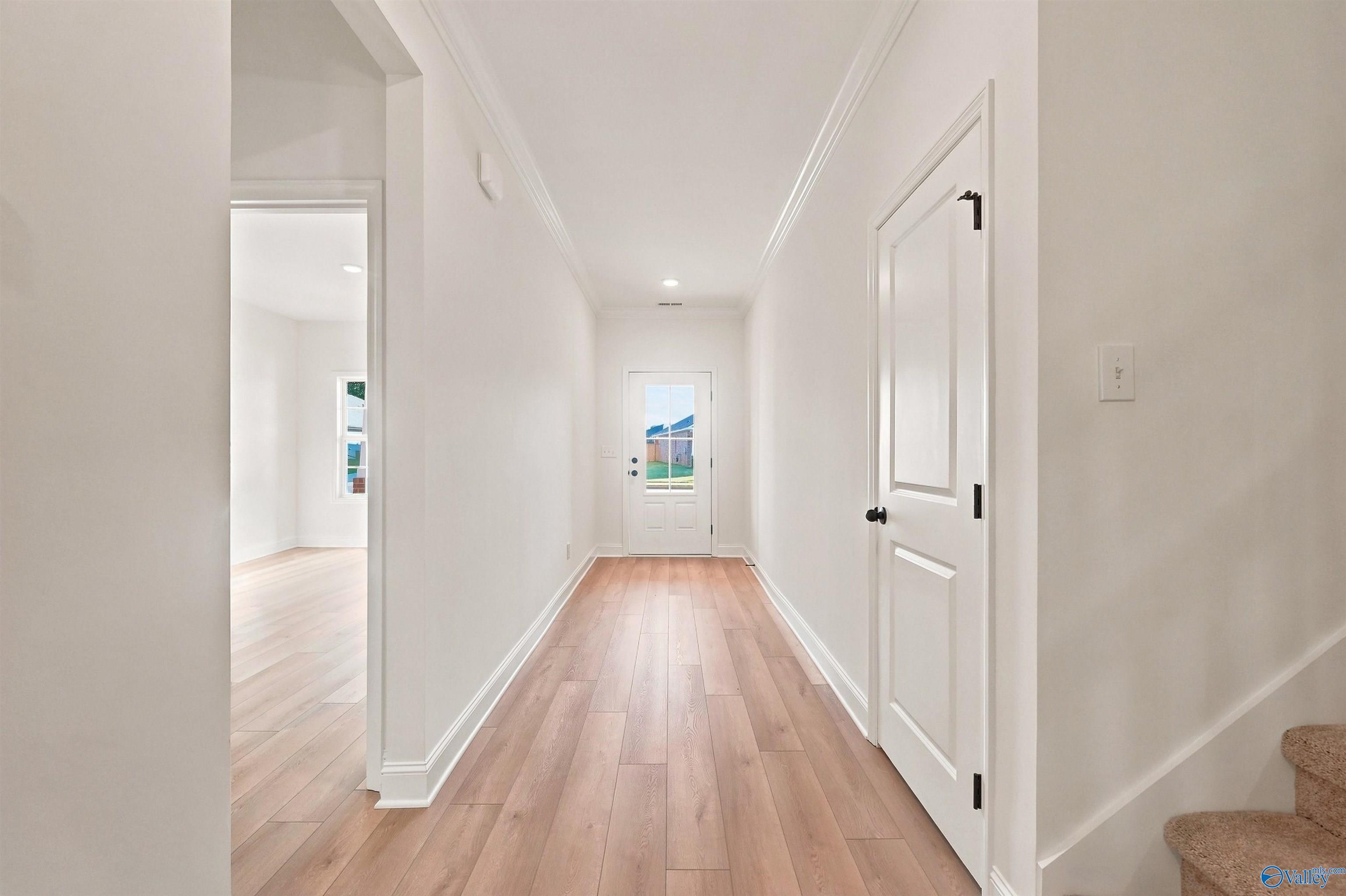 Bright entryway with light wood flooring leading to a glass-paneled front door in The Chelsea C home, Creek Grove, Alabama.