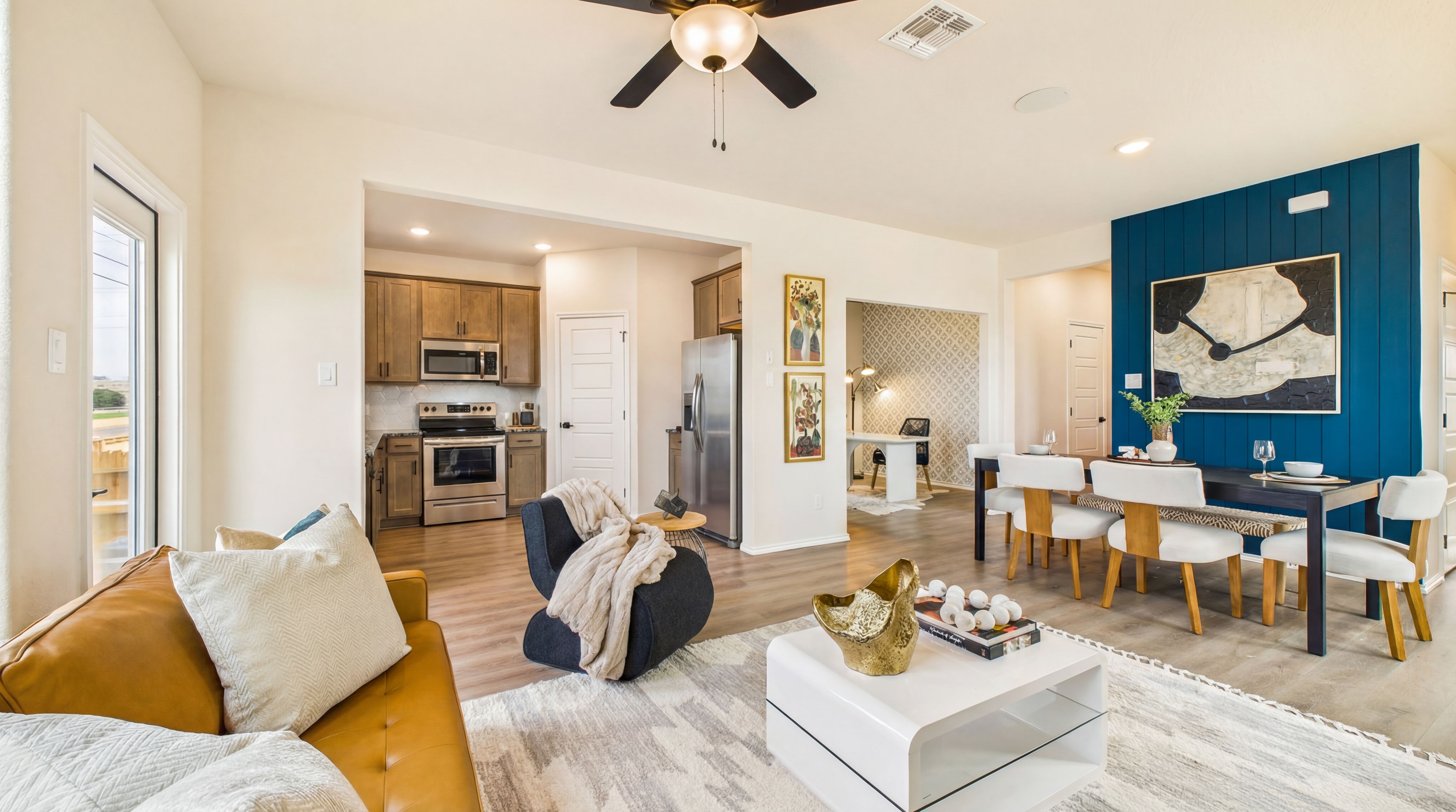 Open-concept living room and kitchen at Meadows at Oak Creek in San Antonio TX with leather sofa, dining table, and blue accent wall