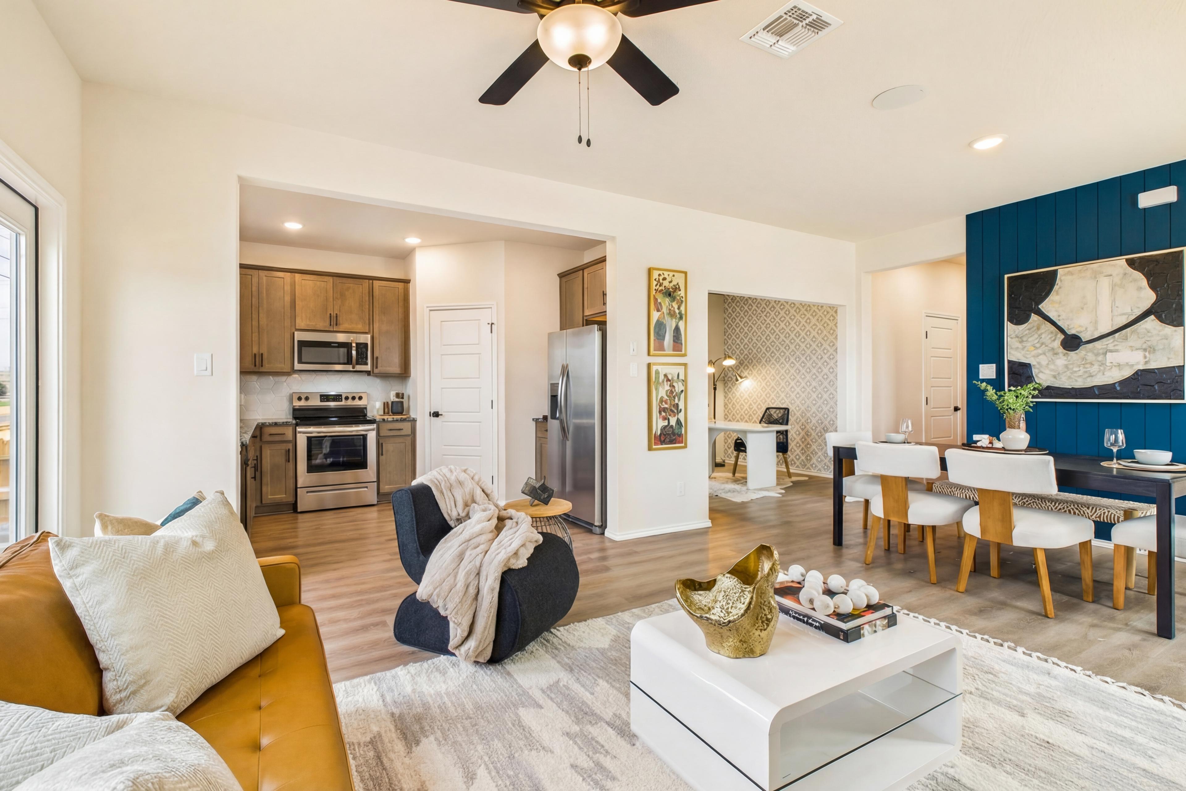 Open-concept living room and kitchen at Meadows at Oak Creek in San Antonio TX with leather sofa, dining table, and blue accent wall