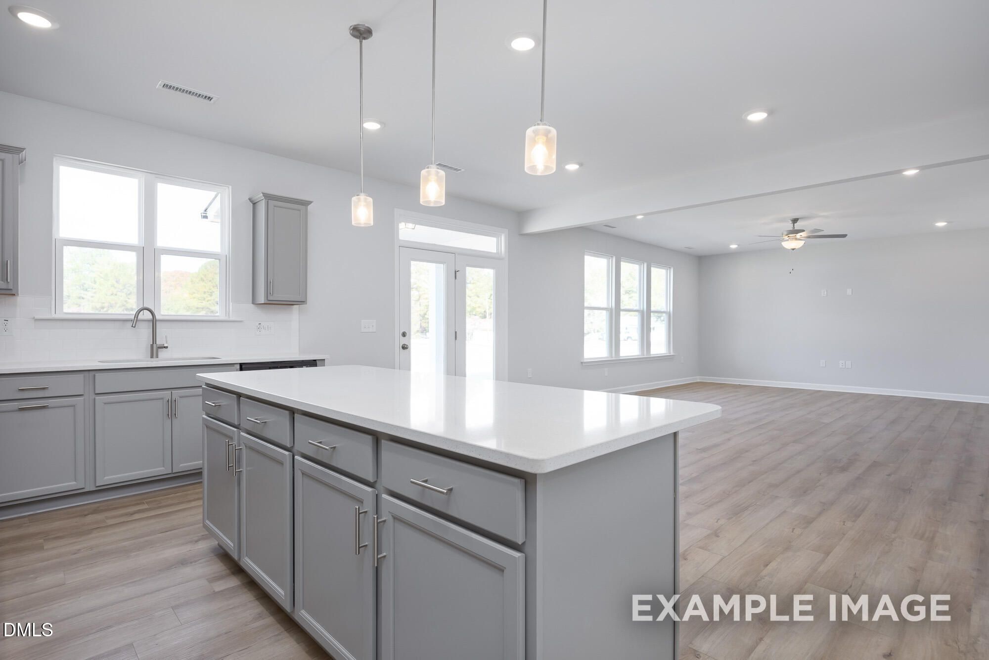 Modern open-concept kitchen with gray shaker cabinets, white quartz island, and stainless sink in Davidson Homes The Hickory II B, Lillington, NC