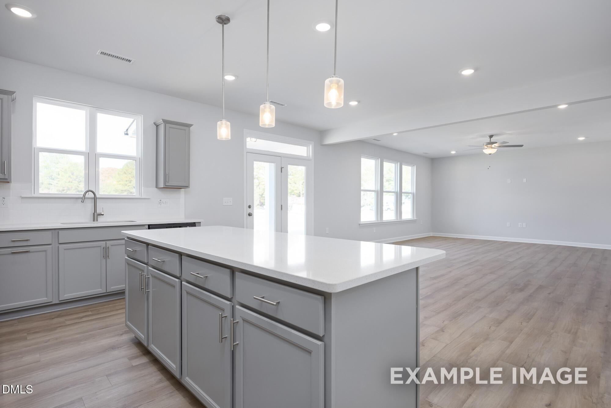 Modern open-concept kitchen with gray shaker cabinets, white quartz island, and stainless sink in Davidson Homes The Hickory II B, Lillington, NC