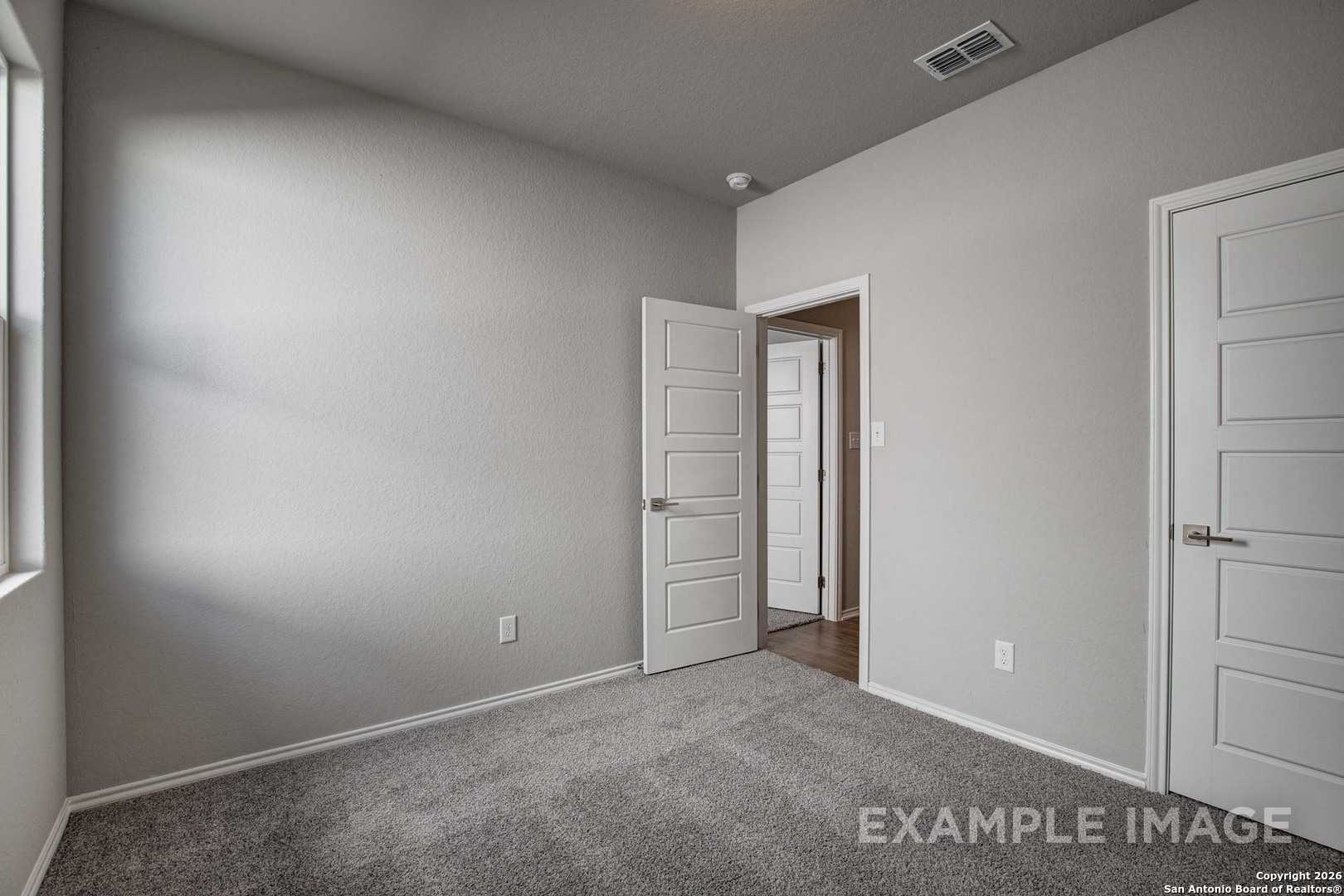 Cozy secondary bedroom with gray walls, carpet floor, and adjacent closet door in Davidson Homes The Frio B, Agave San Antonio