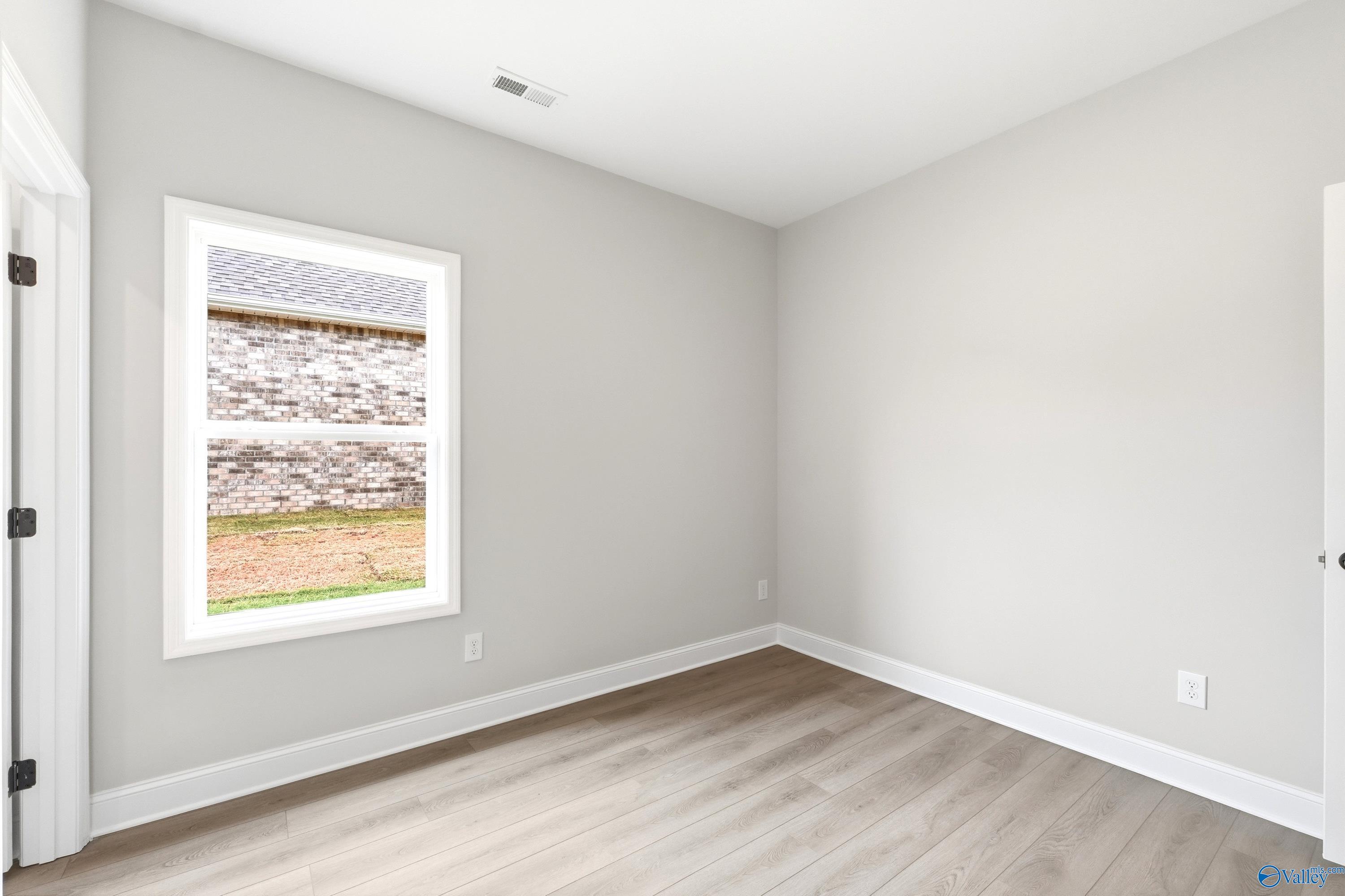 Bright secondary bedroom with wood-look flooring in The Daphne C floor plan at Flint Meadows, New Market, Alabama.