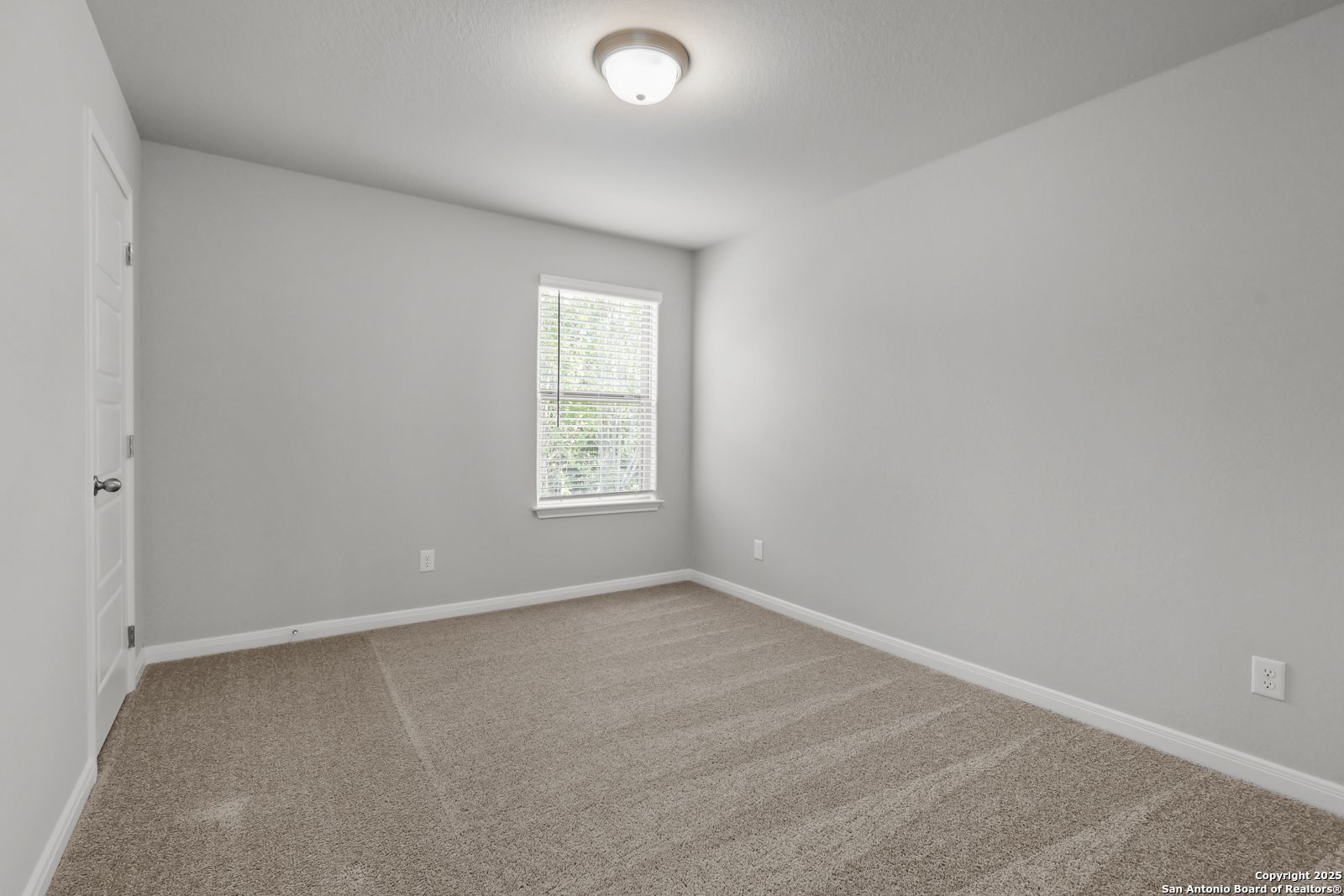 Spacious empty bedroom with beige carpet, gray walls, and window blinds in Davidson Homes The Gillian C, San Antonio