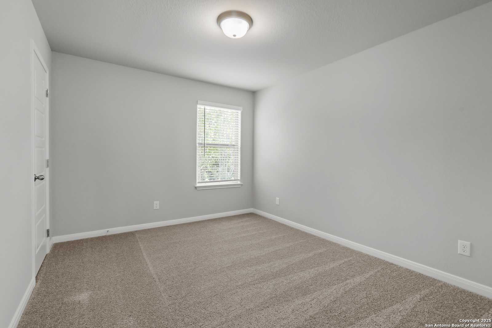 Spacious empty bedroom with beige carpet, gray walls, and window blinds in Davidson Homes The Gillian C, San Antonio