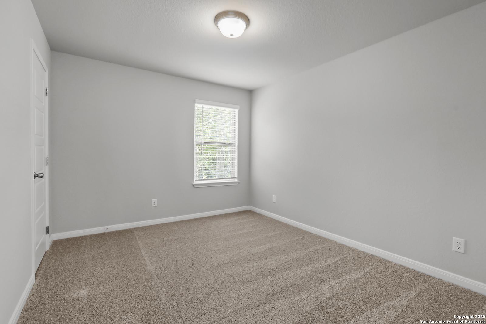 Spacious empty bedroom with beige carpet, gray walls, and window blinds in Davidson Homes The Gillian C, San Antonio