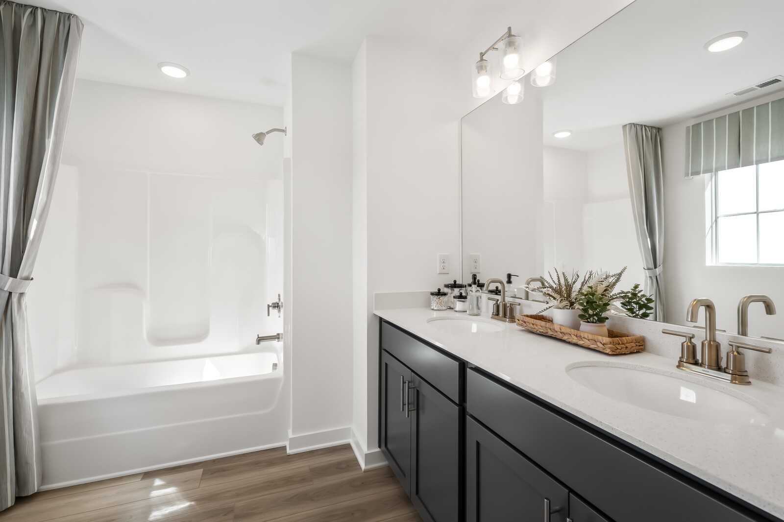 Elegant master bathroom with double vanity, soaking tub, walk-in shower, and plants in Davidson Homes Cumberland B, Gallatin, TN