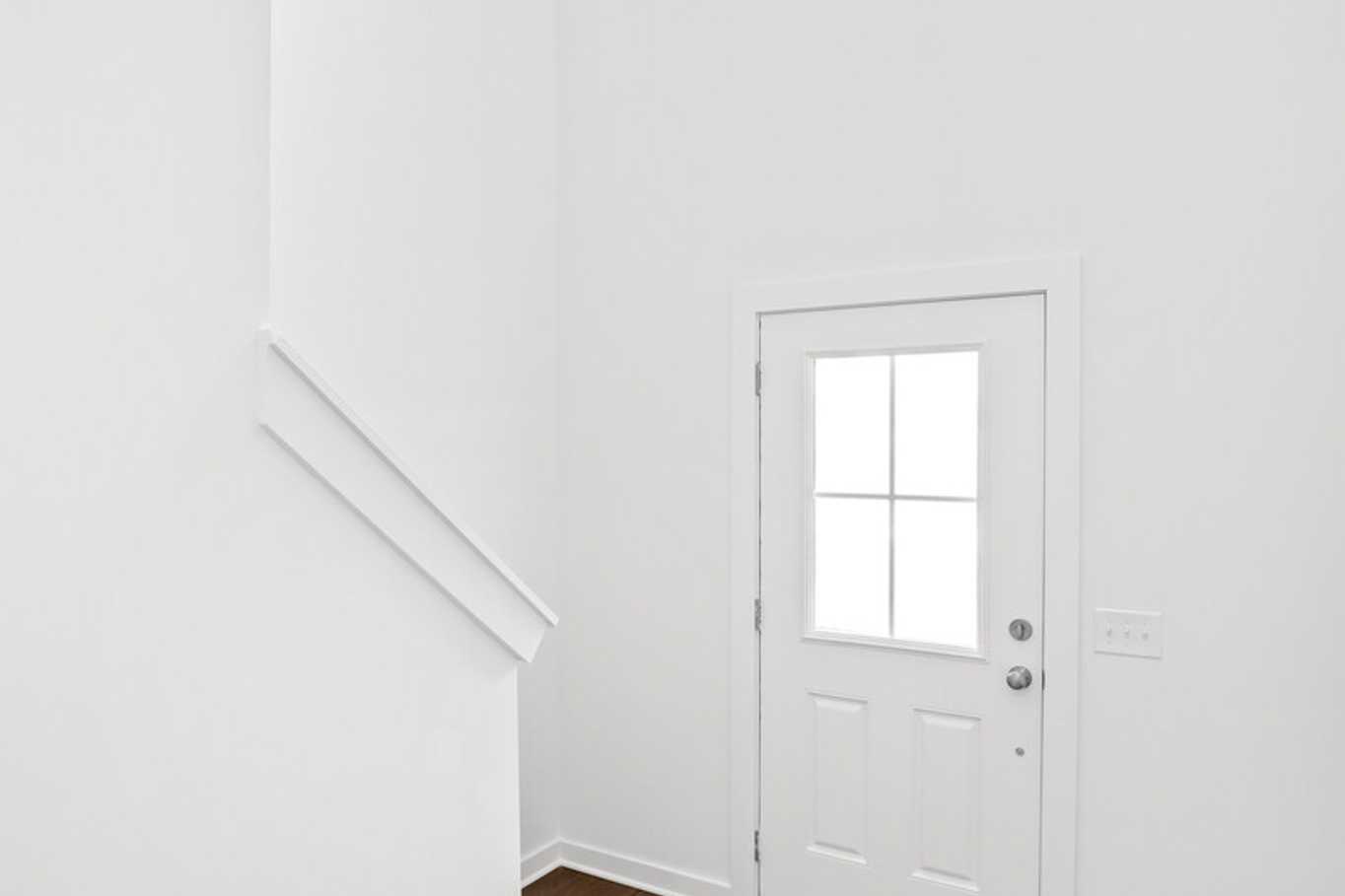 Spacious two-story foyer in The Grayson C home featuring white walls, hardwood floors, and curved staircase
