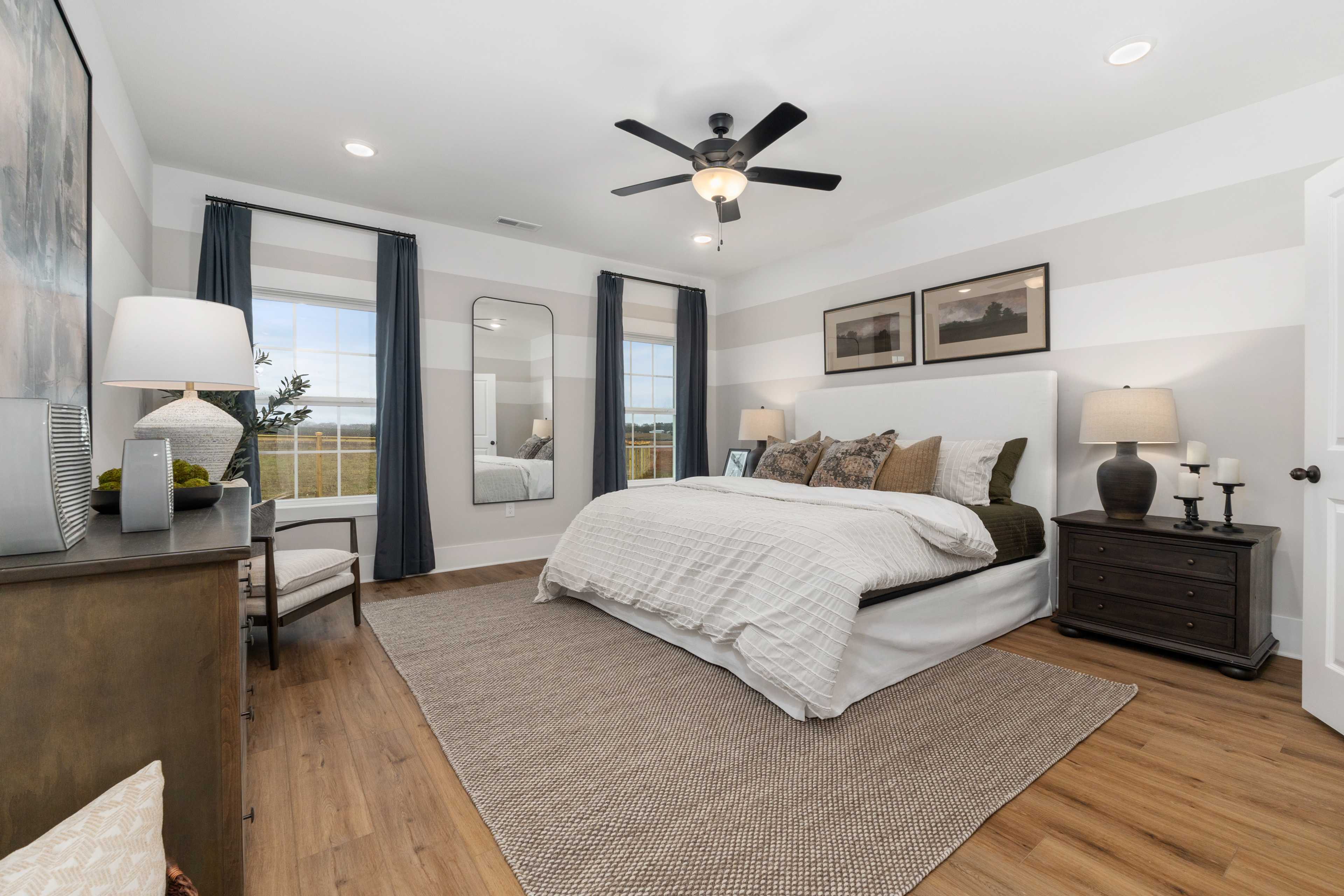 Spacious master bedroom at Kendall Farms in Toney AL with king bed, hardwood floors, ceiling fan, and neutral decor