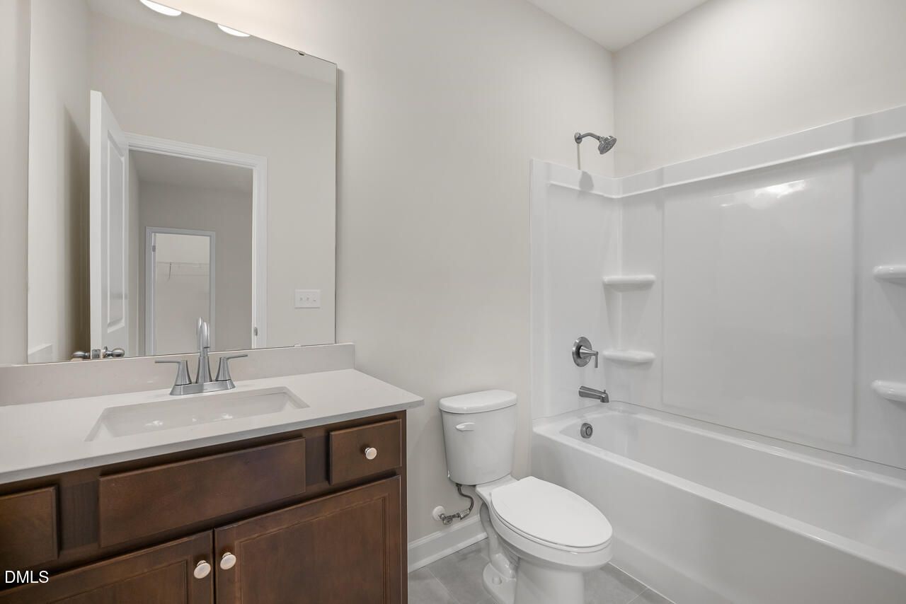 Modern bathroom with vanity, mirror, and tub-shower combo in The Hickory II B plan by Davidson Homes, Aberdeen, NC.