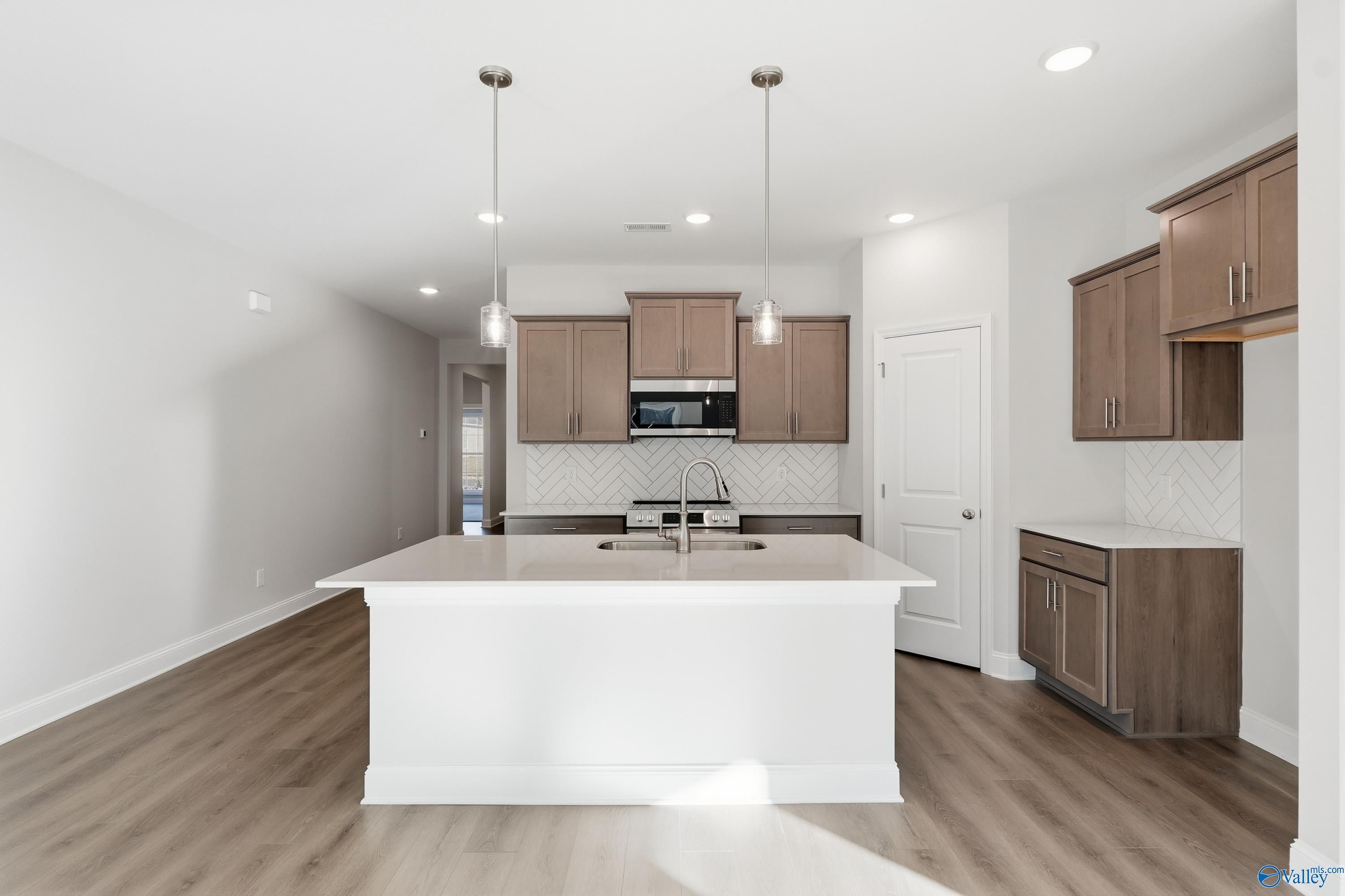 Modern open-concept kitchen with white quartz island, stainless appliances, subway tile backsplash in Daphne C home, Arab, AL