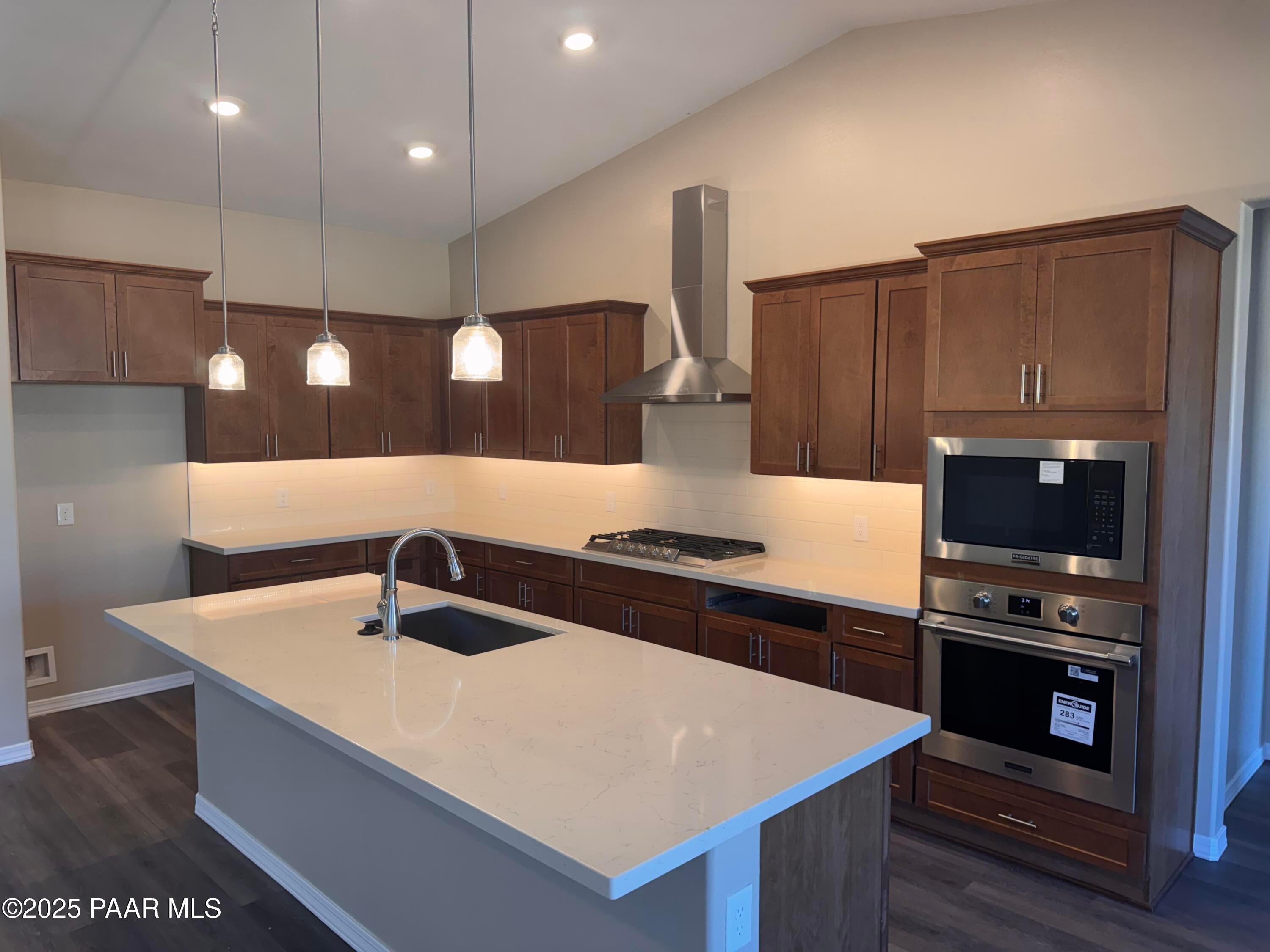 Modern kitchen featuring quartz island sink, stainless steel range, and shaker cabinets in Davidson Homes The Sunrise II A, Prescott, AZ