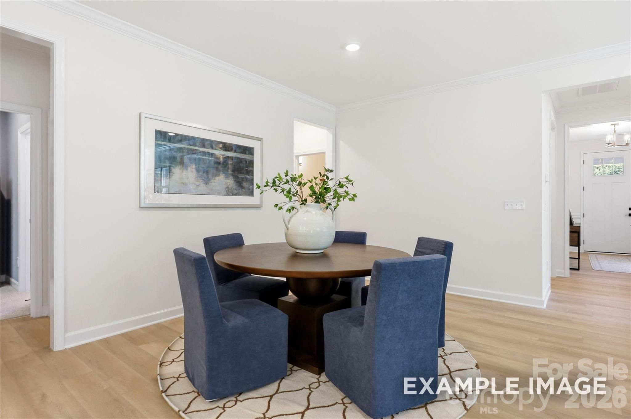 Bright dining area with round wood table, navy chairs, and hardwood floors in Davidson Homes Aspen B, Mooresville, NC