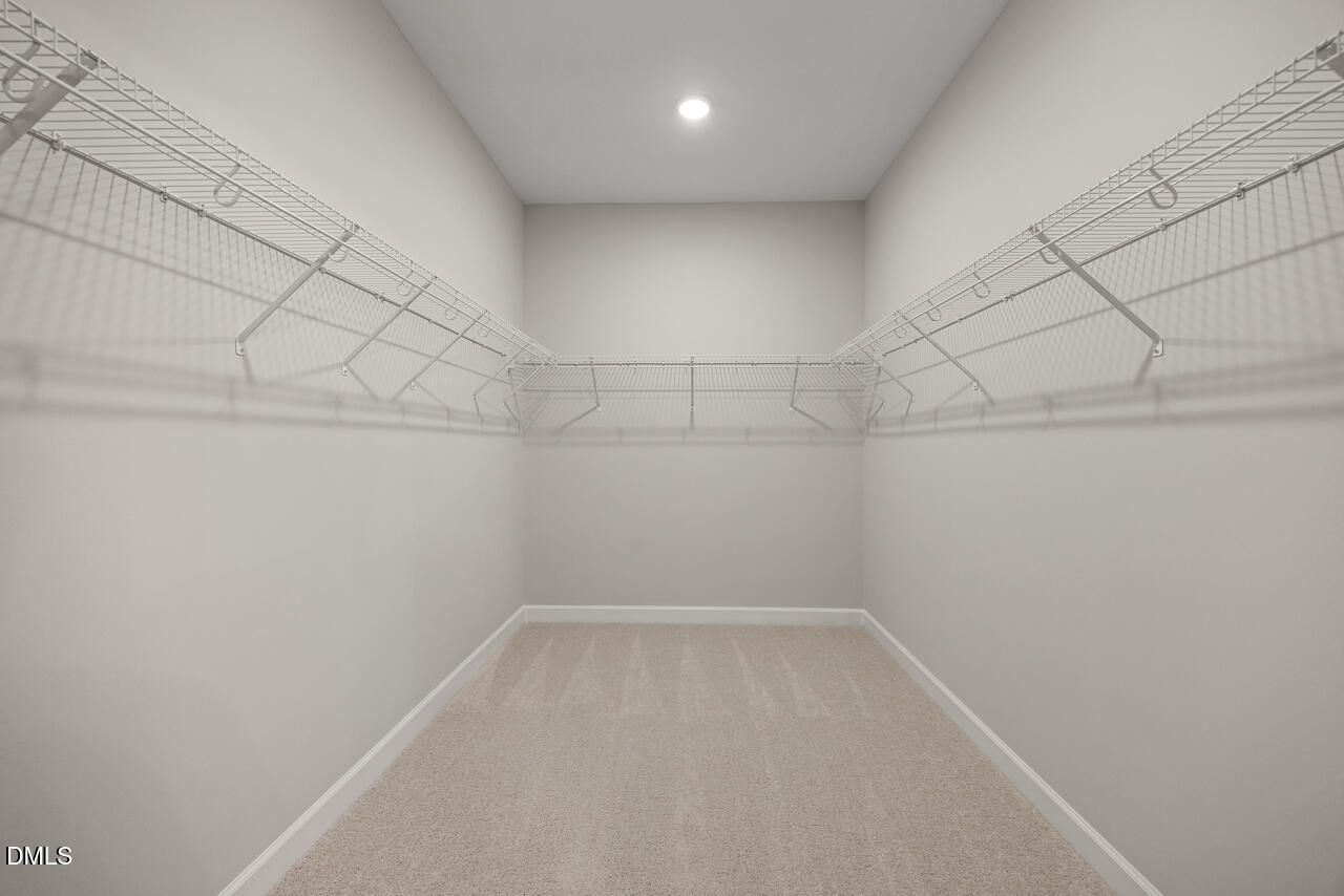 Walk-in closet with white wire shelving and plush carpet in The Chestnut floor plan, Montrose, Aberdeen, North Carolina.