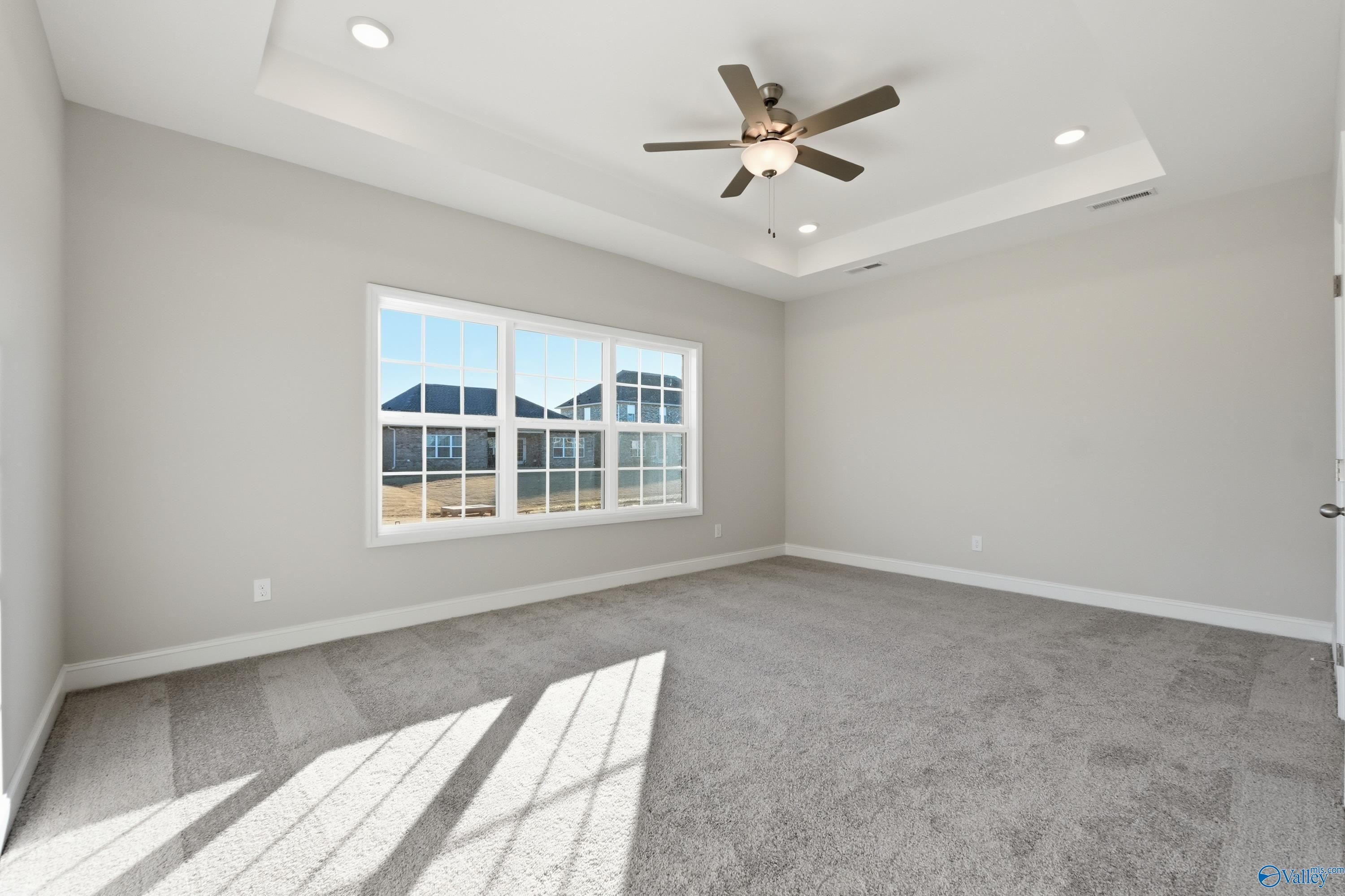 Bright bedroom with large sunny windows, ceiling fan, and gray carpet in Davidson Homes The Montgomery B, Toney, Alabama