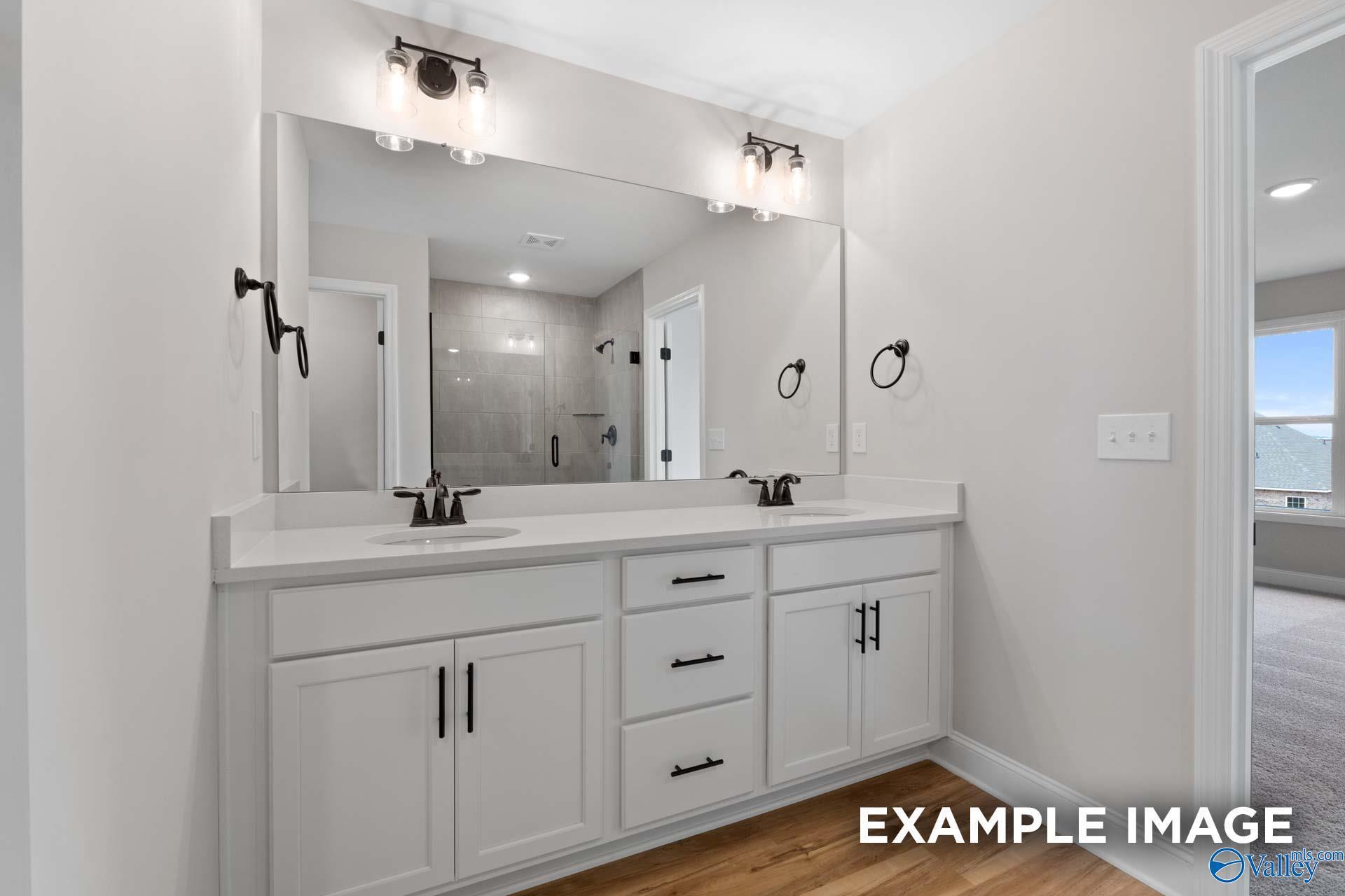 Modern primary bathroom with double vanity, white cabinets, and tiled shower in The Shelby B plan, Jaguar Hills, Huntsville.