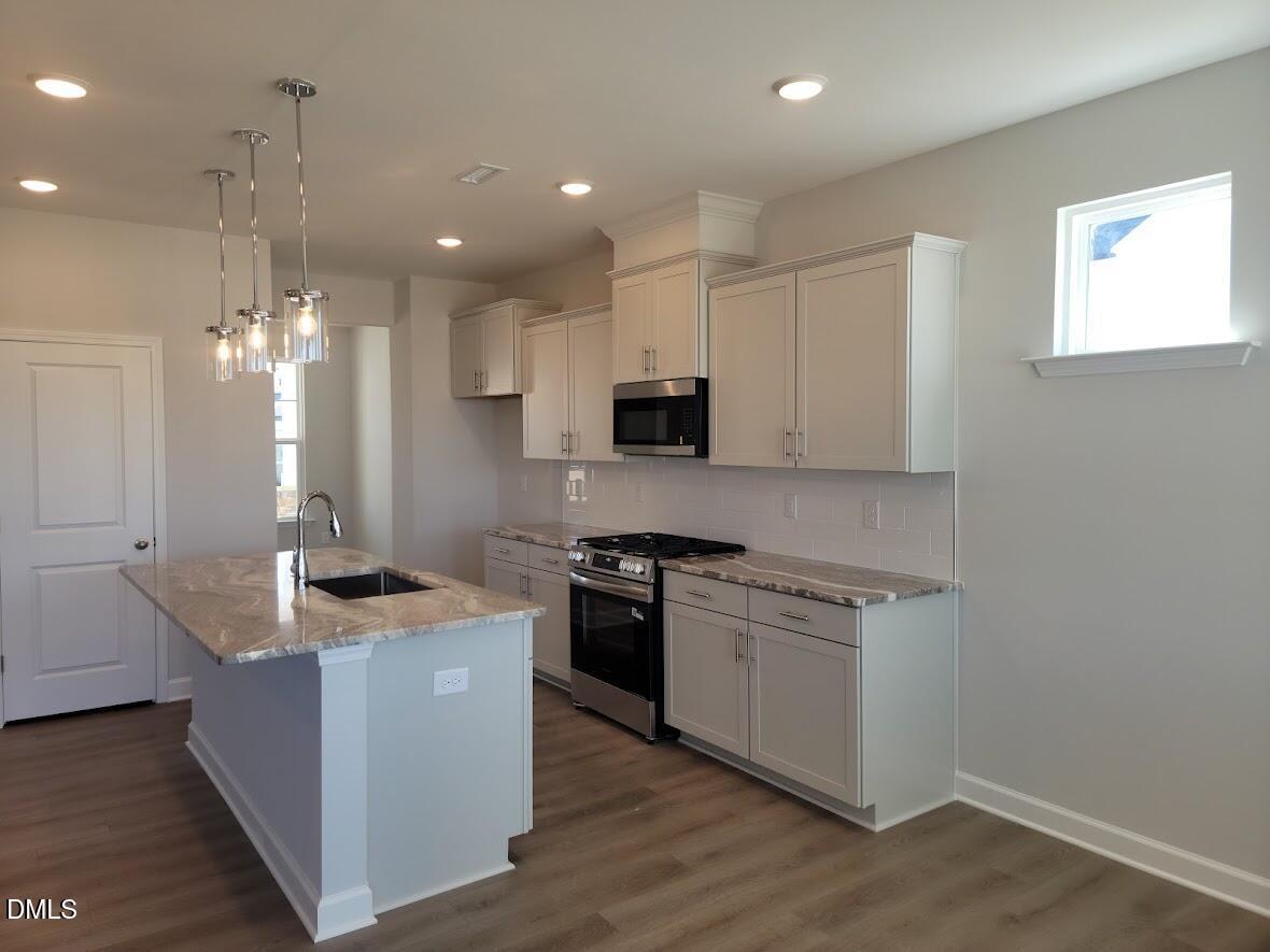 Modern kitchen featuring white shaker cabinets, granite island sink, stainless steel appliances in Davidson Homes The Willow G, Angier, NC