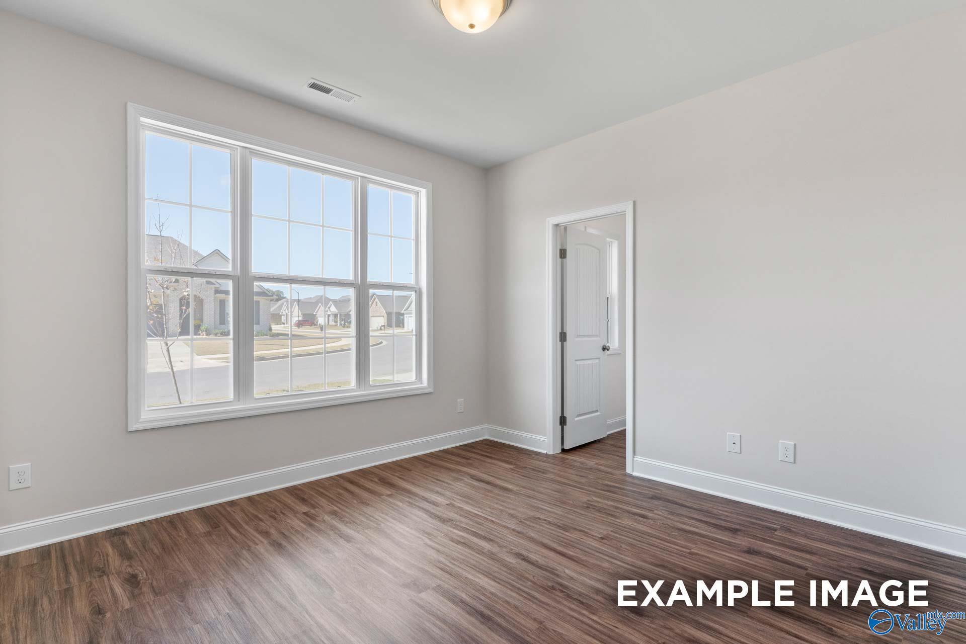 Bright living room with large windows, hardwood floors, and neutral walls in The Montgomery C, Creekside, Harvest, Alabama