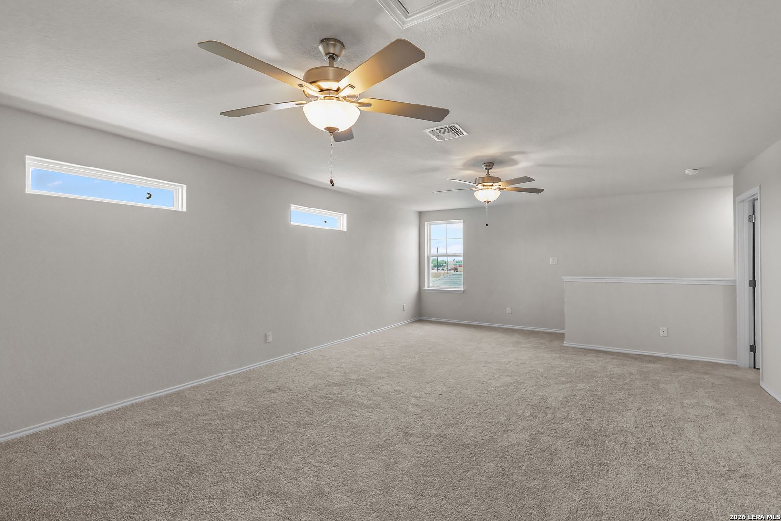 Spacious carpeted game room with ceiling fans in San Marcos F floor plan at Rayburn Valley, San Antonio, Texas.