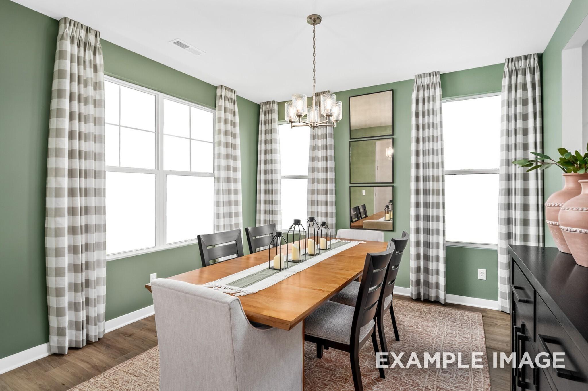 Dining room with green walls and wood table in The Ash A floor plan at Woods Crossing in Gallatin, Tennessee.