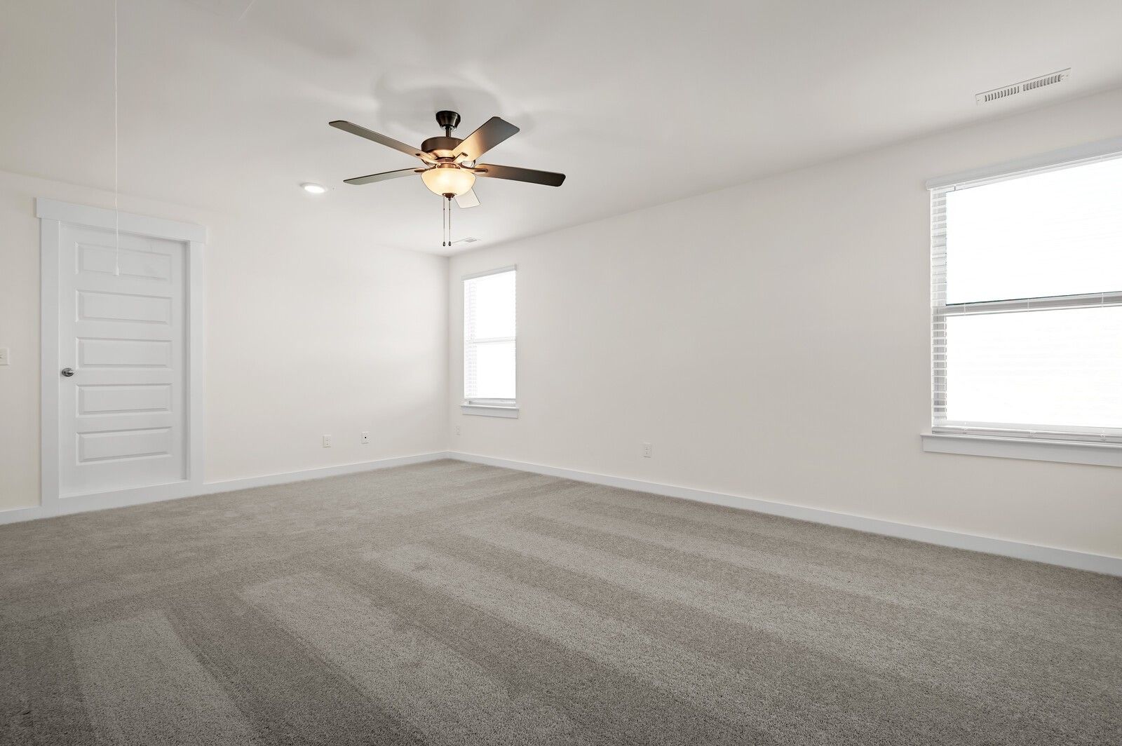 Spacious, carpeted bedroom with ceiling fan in The Ash A floor plan at Woods Crossing in Gallatin, Tennessee.