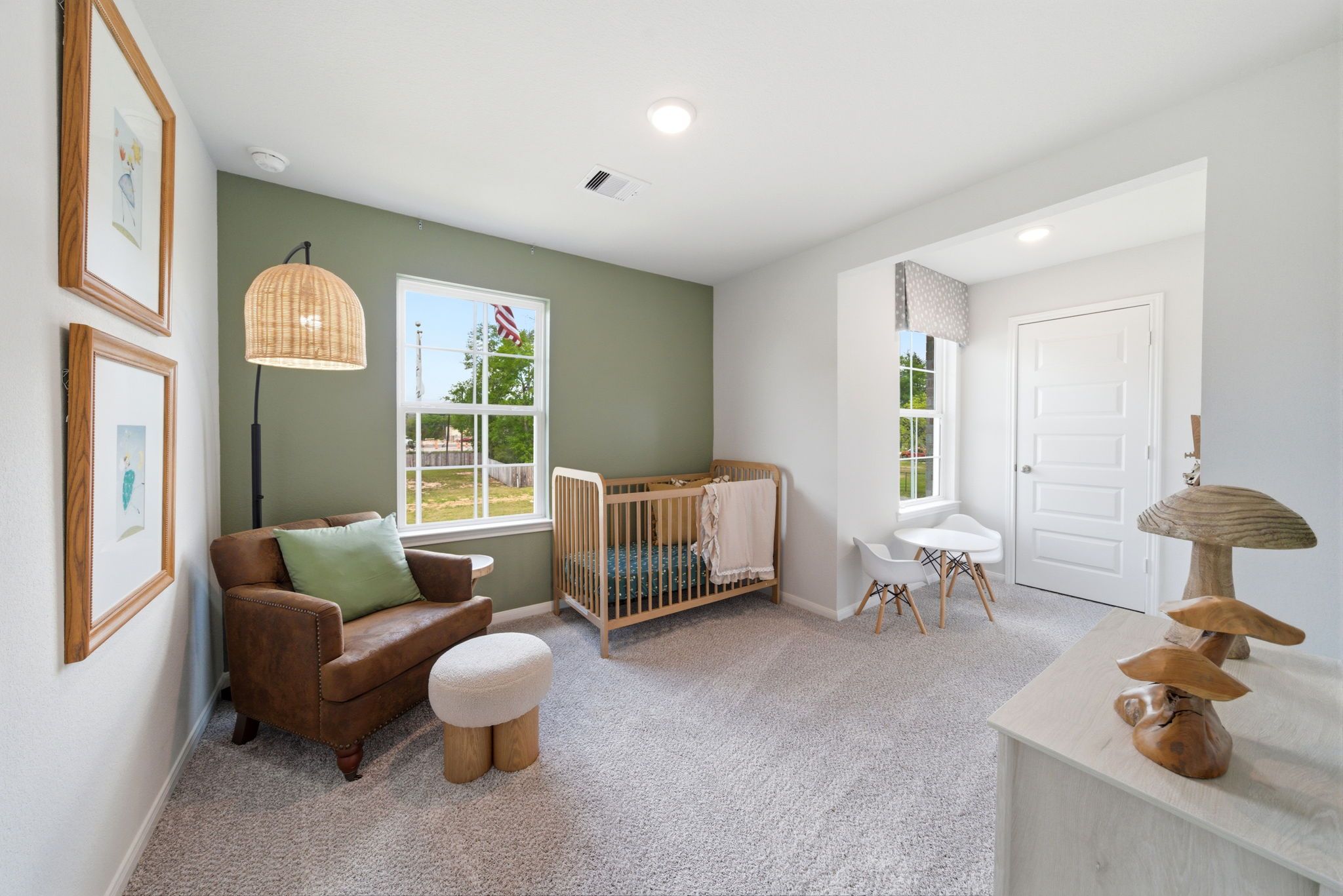 Cozy nursery at Caney Creek Place in Conroe Texas with white wooden crib, green accent wall, rattan lamp