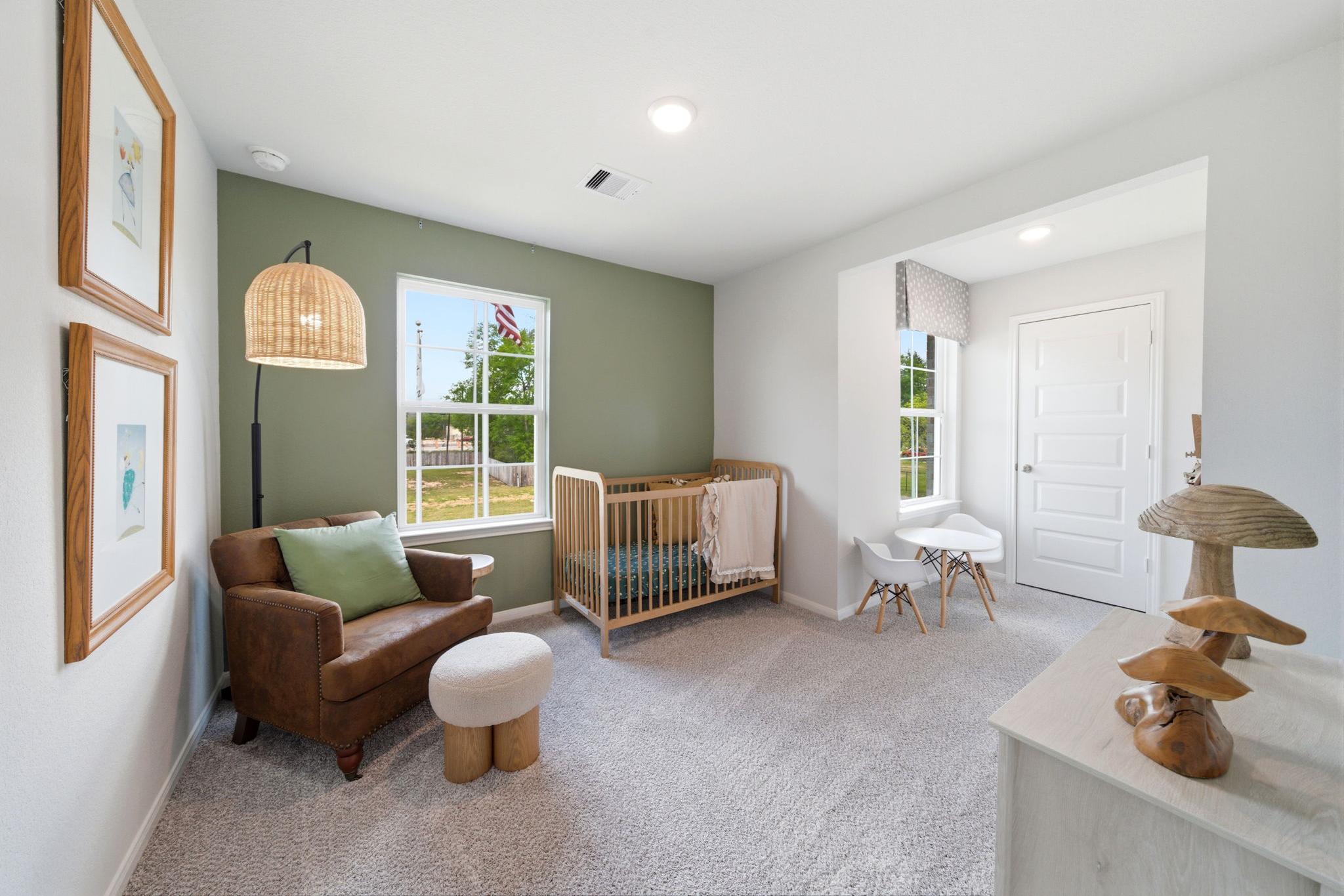 Cozy nursery at Caney Creek Place in Conroe Texas with white wooden crib, green accent wall, rattan lamp