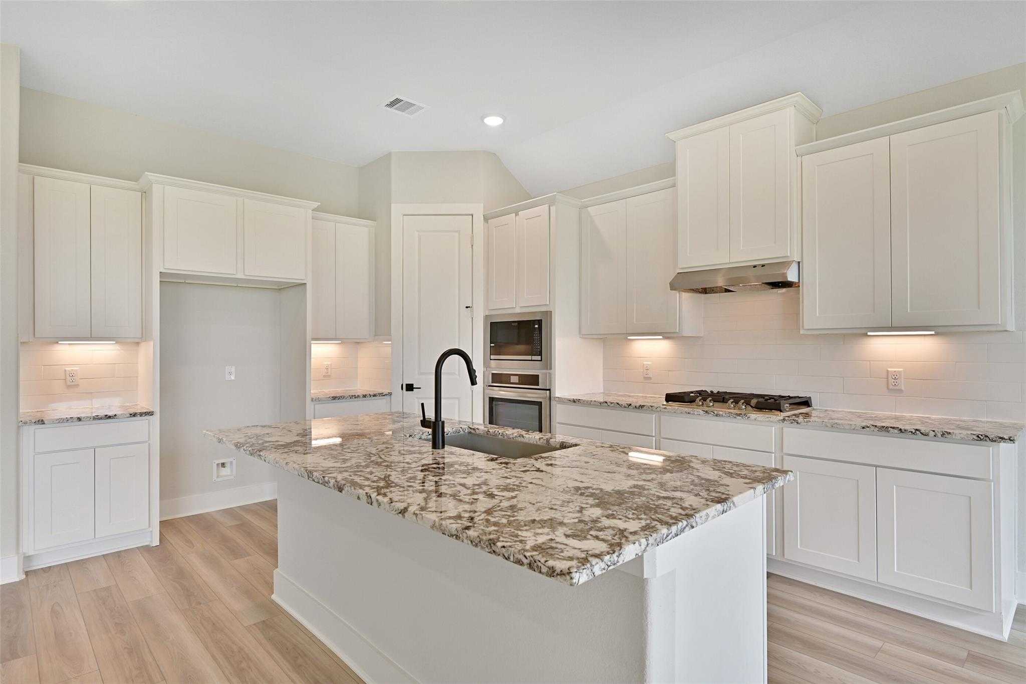 Modern white shaker kitchen with quartz island, stainless steel appliances in Davidson Homes The Edward C, Lago Mar