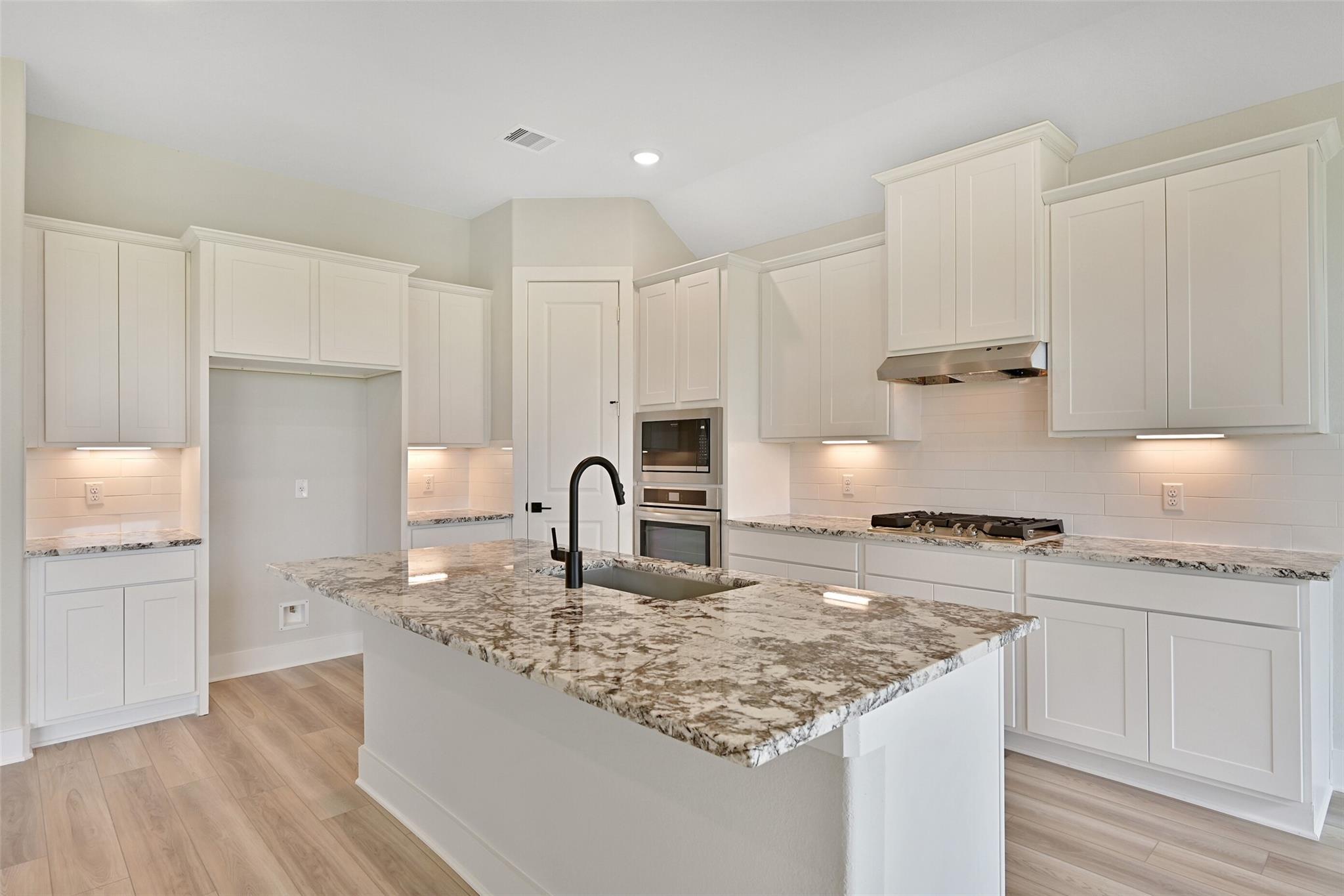 Modern white shaker kitchen with quartz island, stainless steel appliances in Davidson Homes The Edward C, Lago Mar