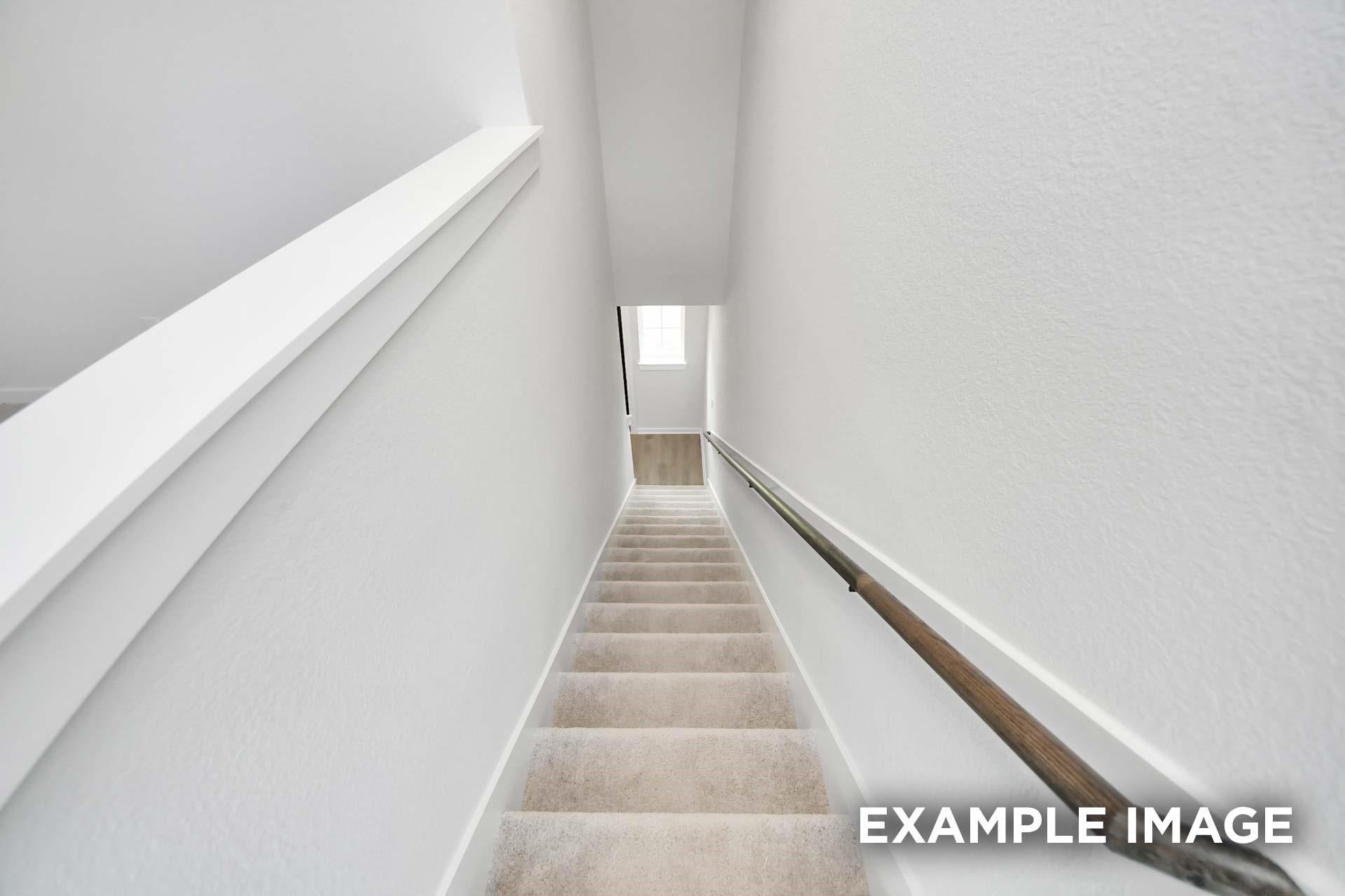 Carpeted staircase with wood handrail leading to upper floor in Davidson Homes The Blanco E 2-story home, Magnolia, Texas