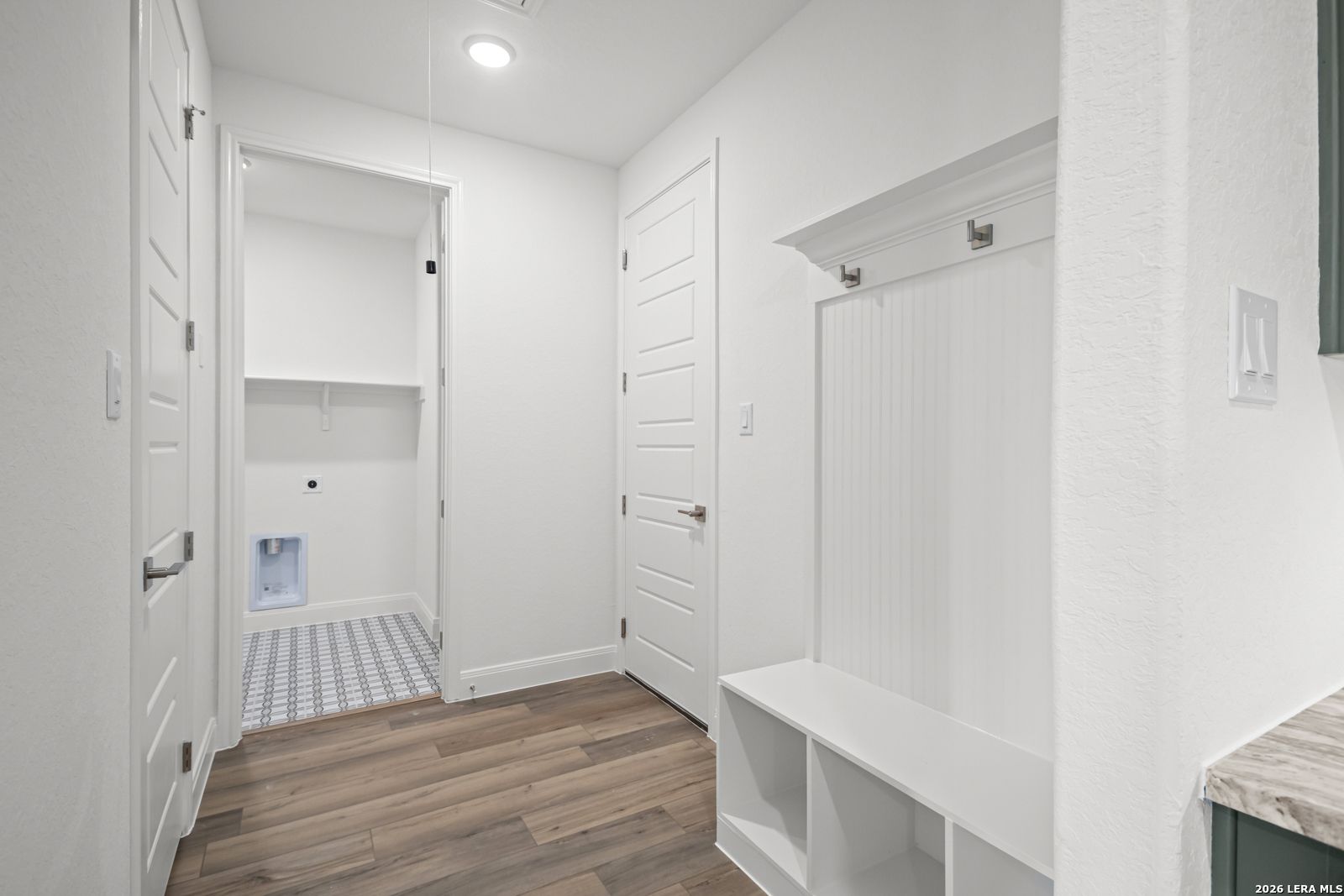 Modern mudroom bench with coat hooks and laundry room in The Lanier G floor plan at The Reserve at Potranco Oaks, TX.