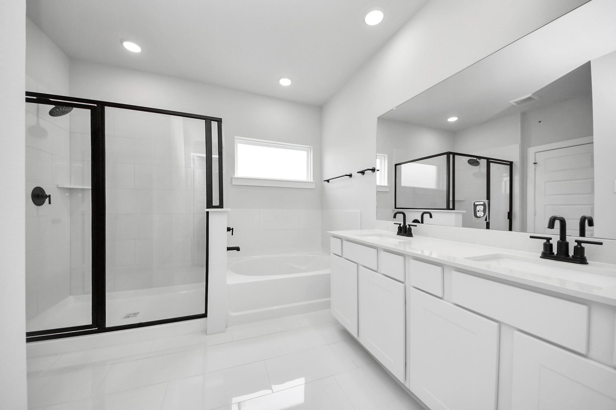 Modern primary bathroom with dual vanities, glass-enclosed shower, and soaking tub in Davidson Homes' The Riviera C plan.