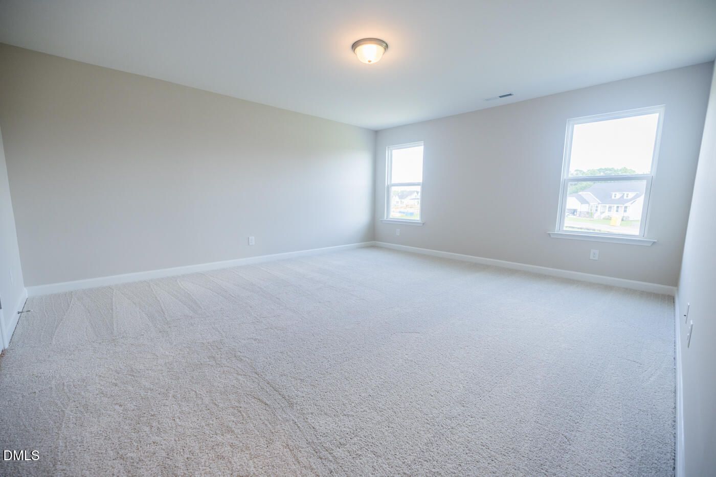 Spacious empty bedroom with neutral walls, beige carpet, double windows, and ceiling light in Davidson Homes The Hickory II C, Zebulon, NC