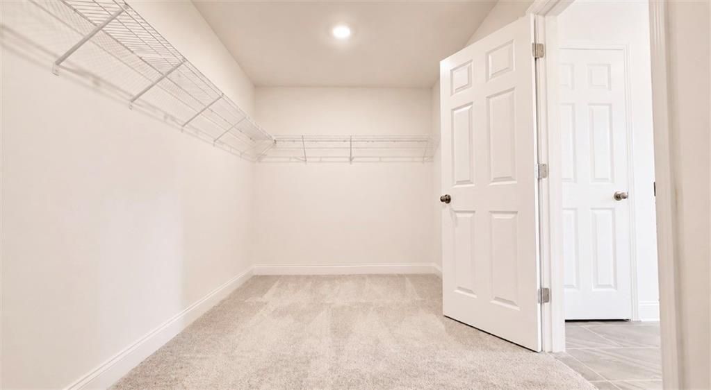 Walk-in closet with wire shelving and carpet in The Hickory C floor plan by Davidson Homes in Wehunt Meadows, Hoschton, GA.