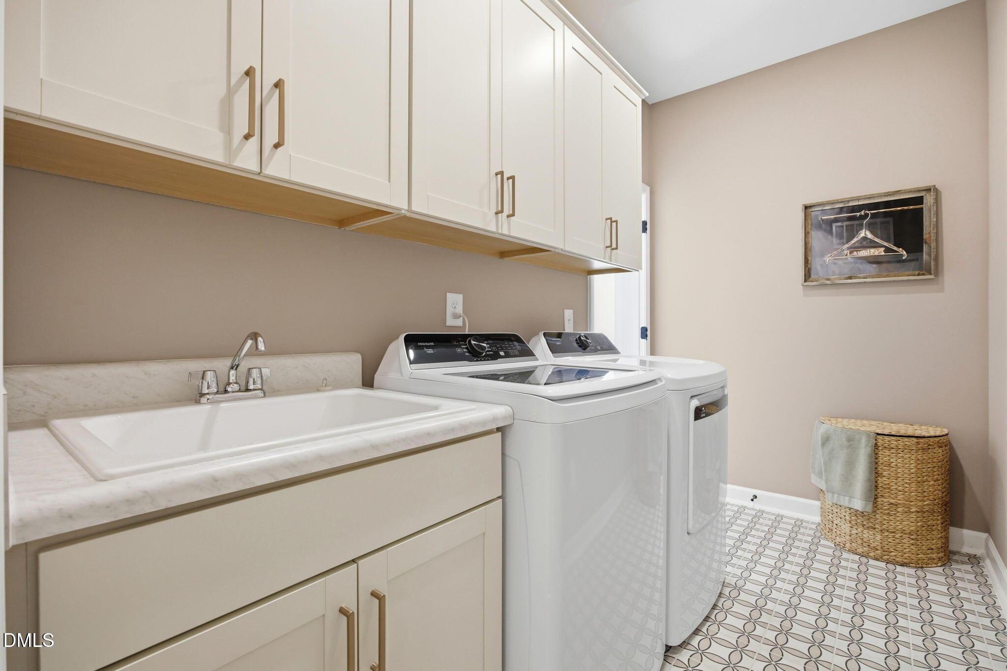 Laundry room with utility sink, white cabinets, and washer-dryer set in The Ashport M floor plan at Wendell Ridge.