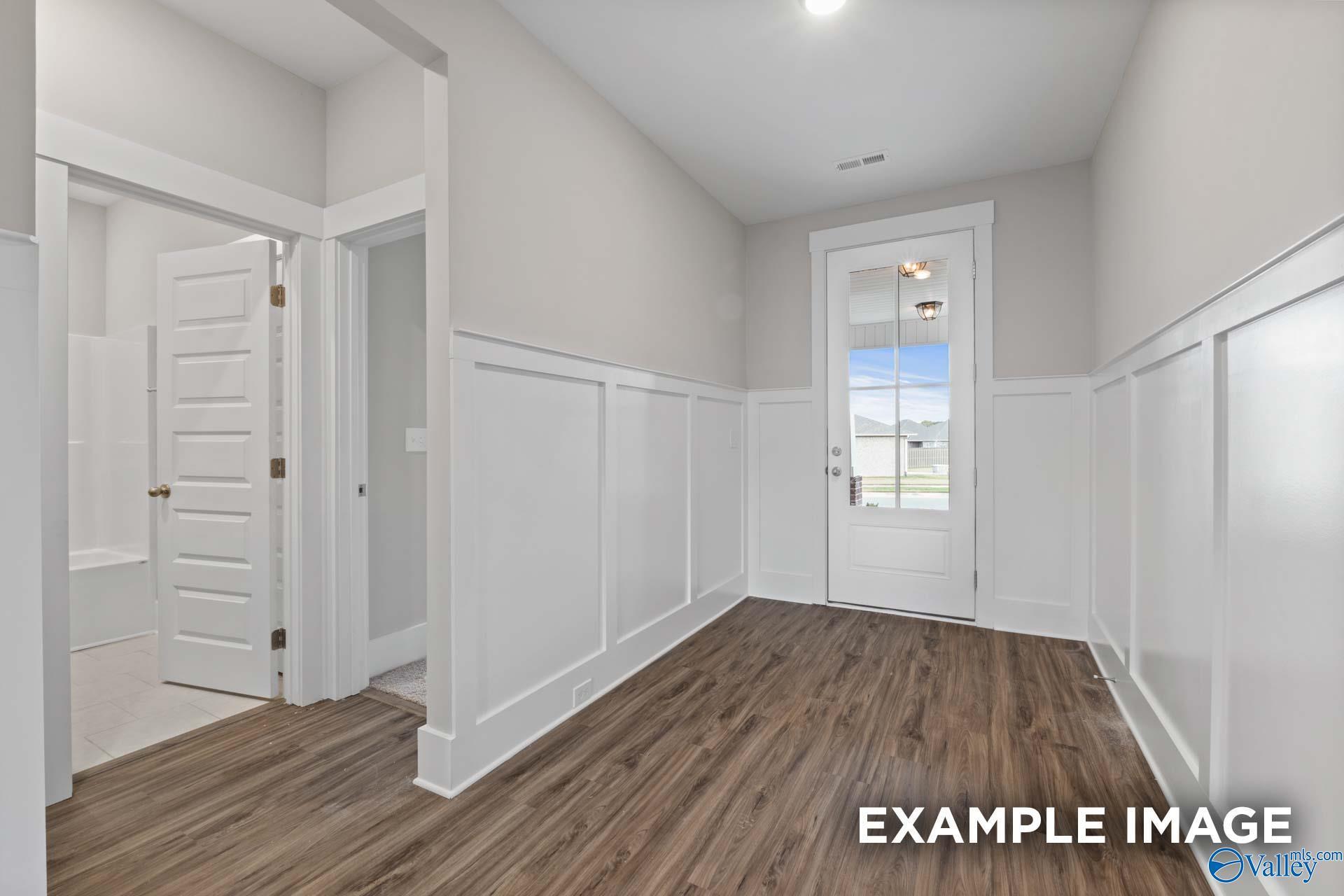 Bright hallway with wainscoting, open bathroom door, and glass back door in 4-bedroom The Harrison home, Cain Park, Hartselle