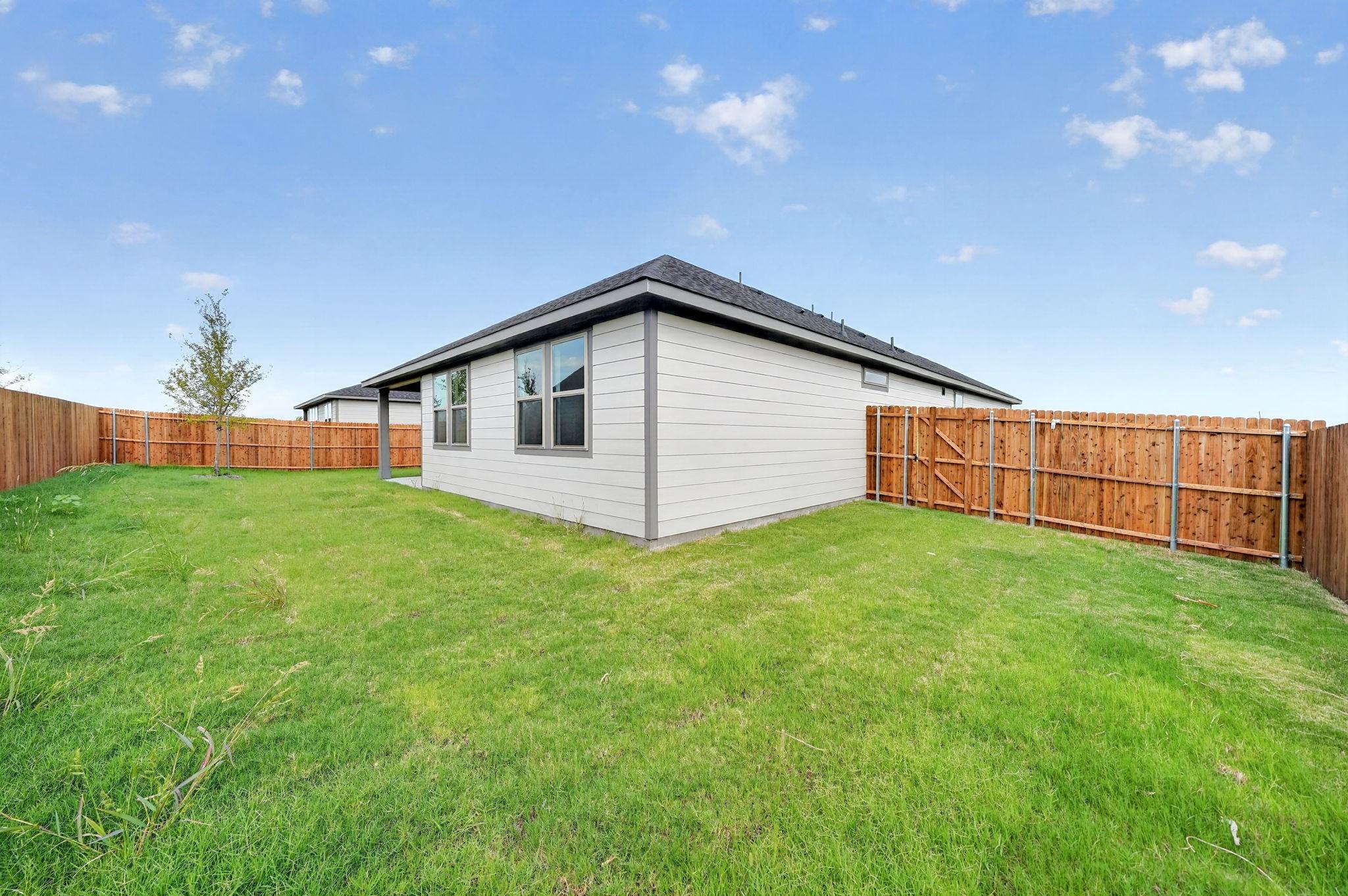 Fenced backyard with lush green lawn at Davidson Homes The Holly F in Meadow Ridge Estates, Josephine, Texas