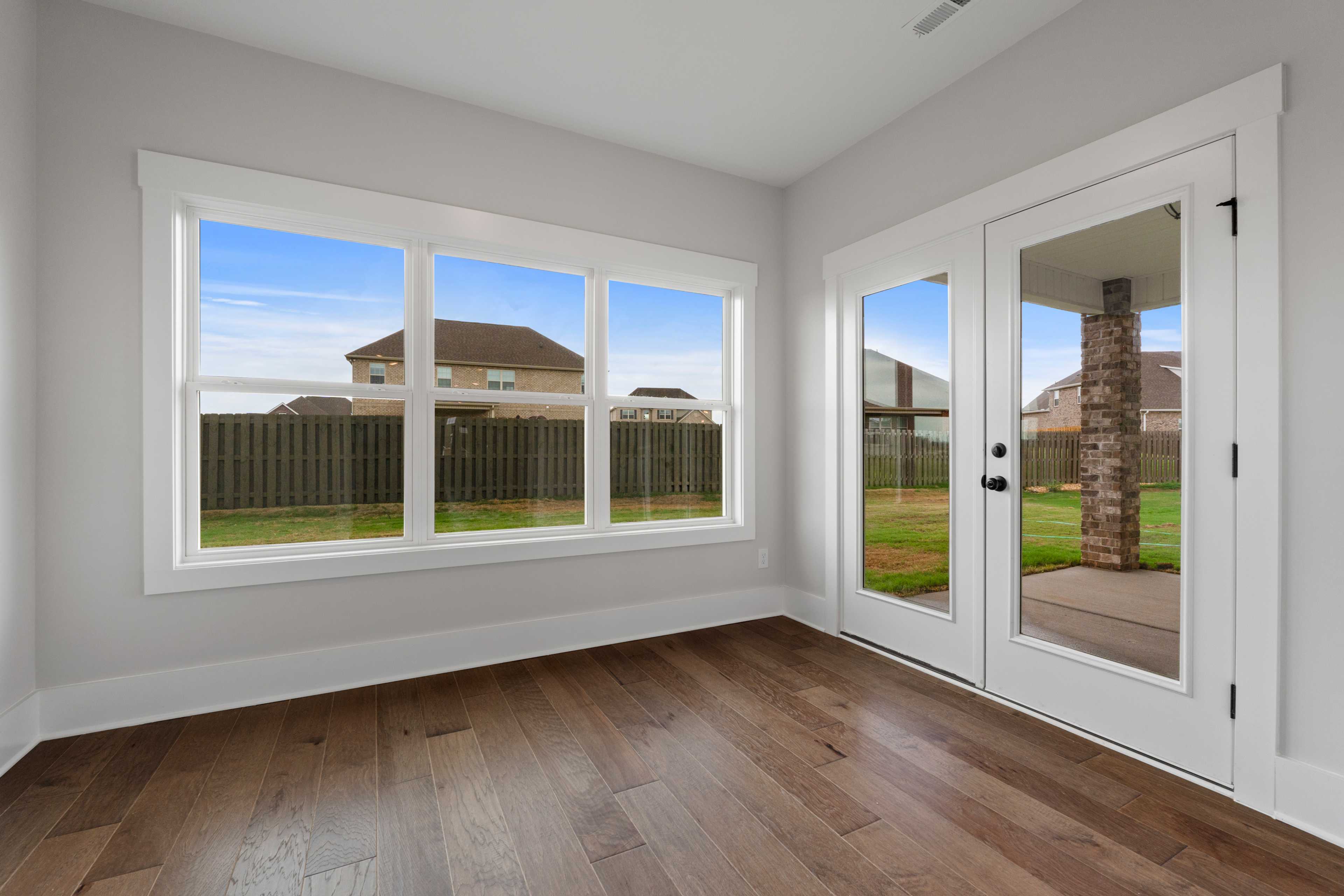 Sunlit study with hardwood floors, large windows, and French doors to patio at The Villas at Barnett's Crossing in Madison, Alabama
